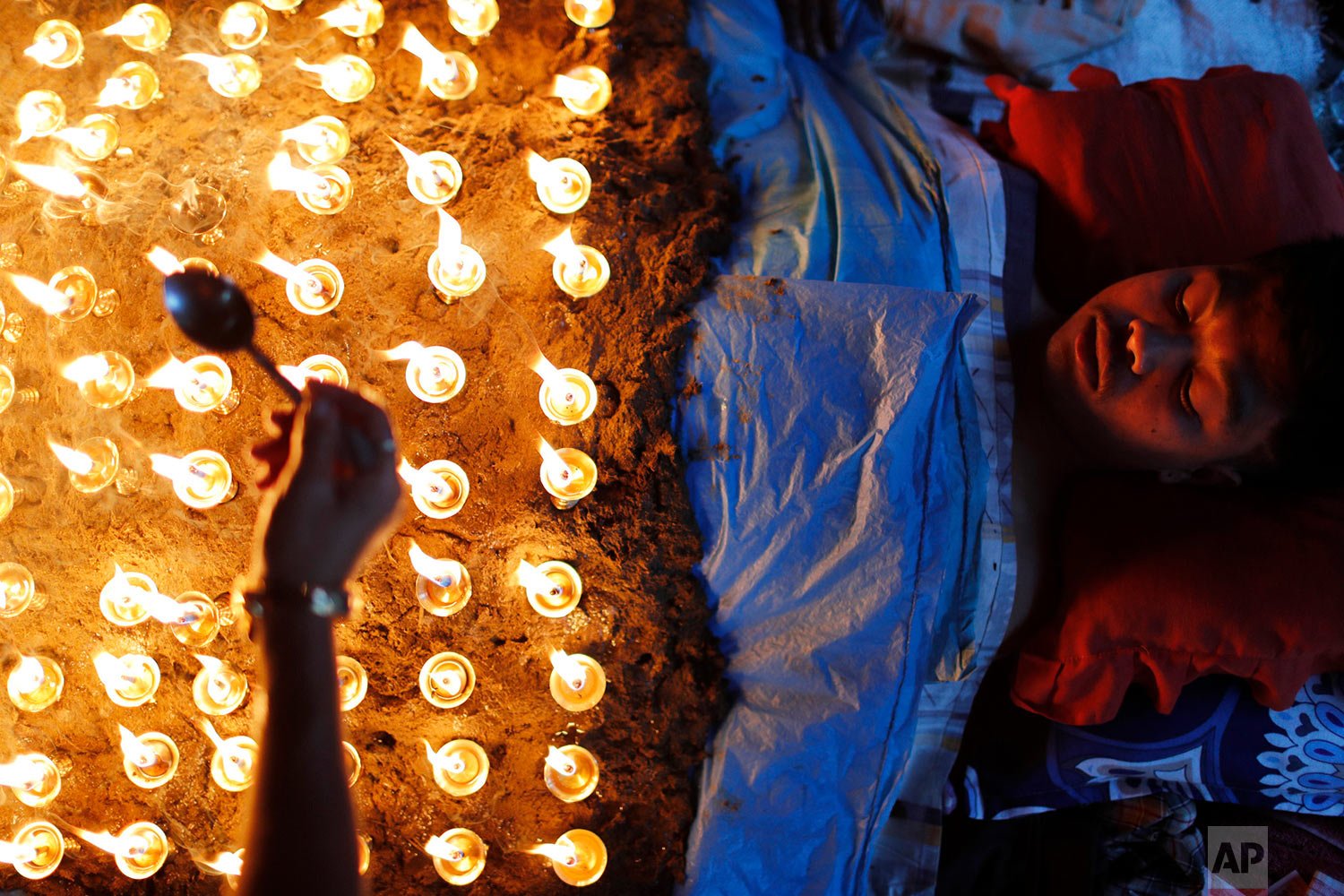  A man lies still as devotees light oil lamps over his body as part of rituals to celebrate the tenth and final day of Dashain festival in Bhaktapur, Nepal, Friday, Oct. 15, 2021. (AP Photo/Niranjan Shrestha) 