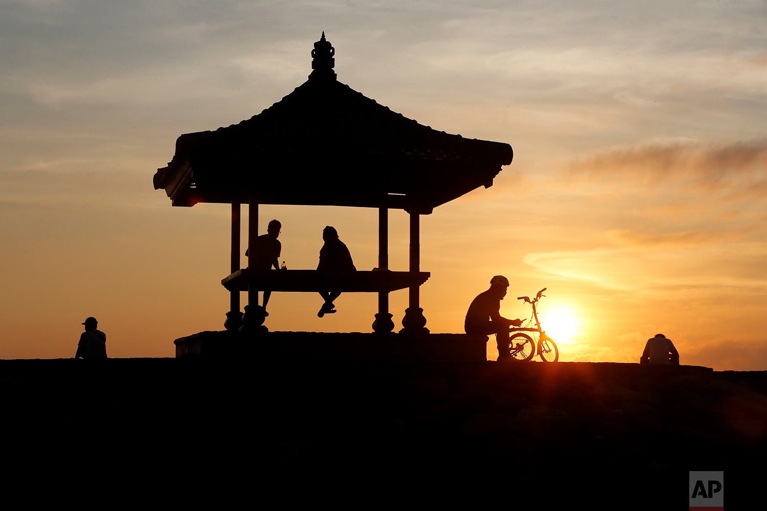  People watch the sun rise at the Sanur Beach in Denpasar, Bali, Indonesia, Thursday, Oct. 28, 2021. (AP Photo/Firdia Lisnawati) 