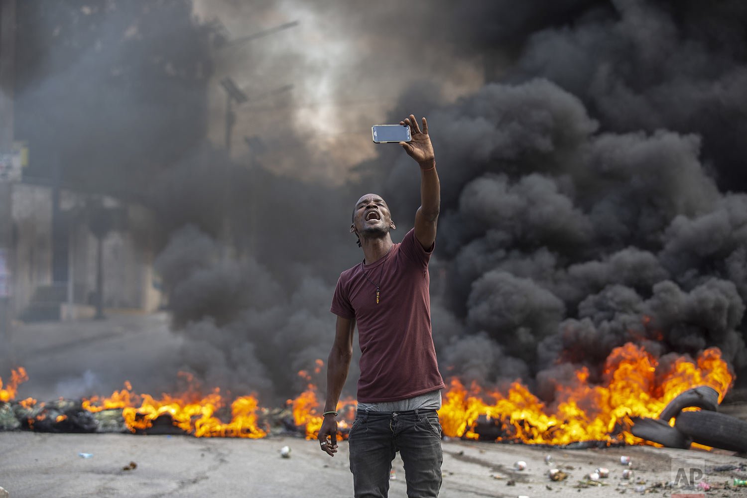  A protester takes a selfie at a burning barricade set by protesters angry over lack of security in Port-au-Prince, Haiti, Oct. 18, 2021. (AP Photo/Odelyn Joseph) 