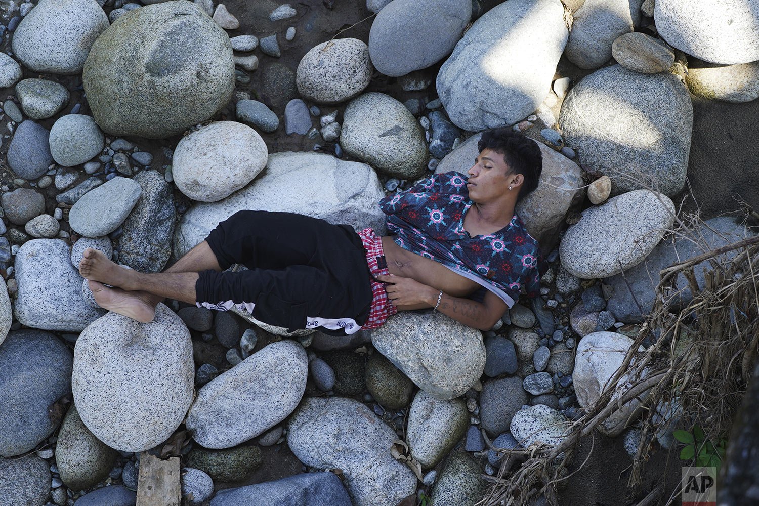  A migrant naps on a bed of rocks on the bank of the Huixtla River in Chiapas state, Mexico, Oct. 26, 2021, on a day of rest during a migrant caravan heading north to the U.S. border. (AP Photo/Marco Ugarte) 