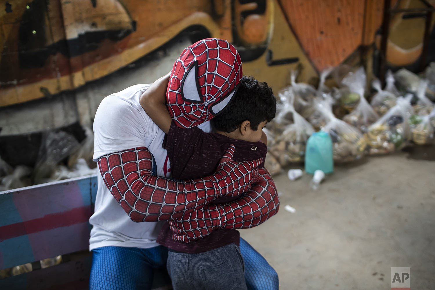 A volunteer dressed as Spiderman embraces a child in the Jardim Gramacho favela of Rio de Janeiro, Brazil, Oct. 30, 2021, during a food kit delivery donated by the non-governmental organization "Covid Sem Fome" that works to fight hunger. (AP Photo/