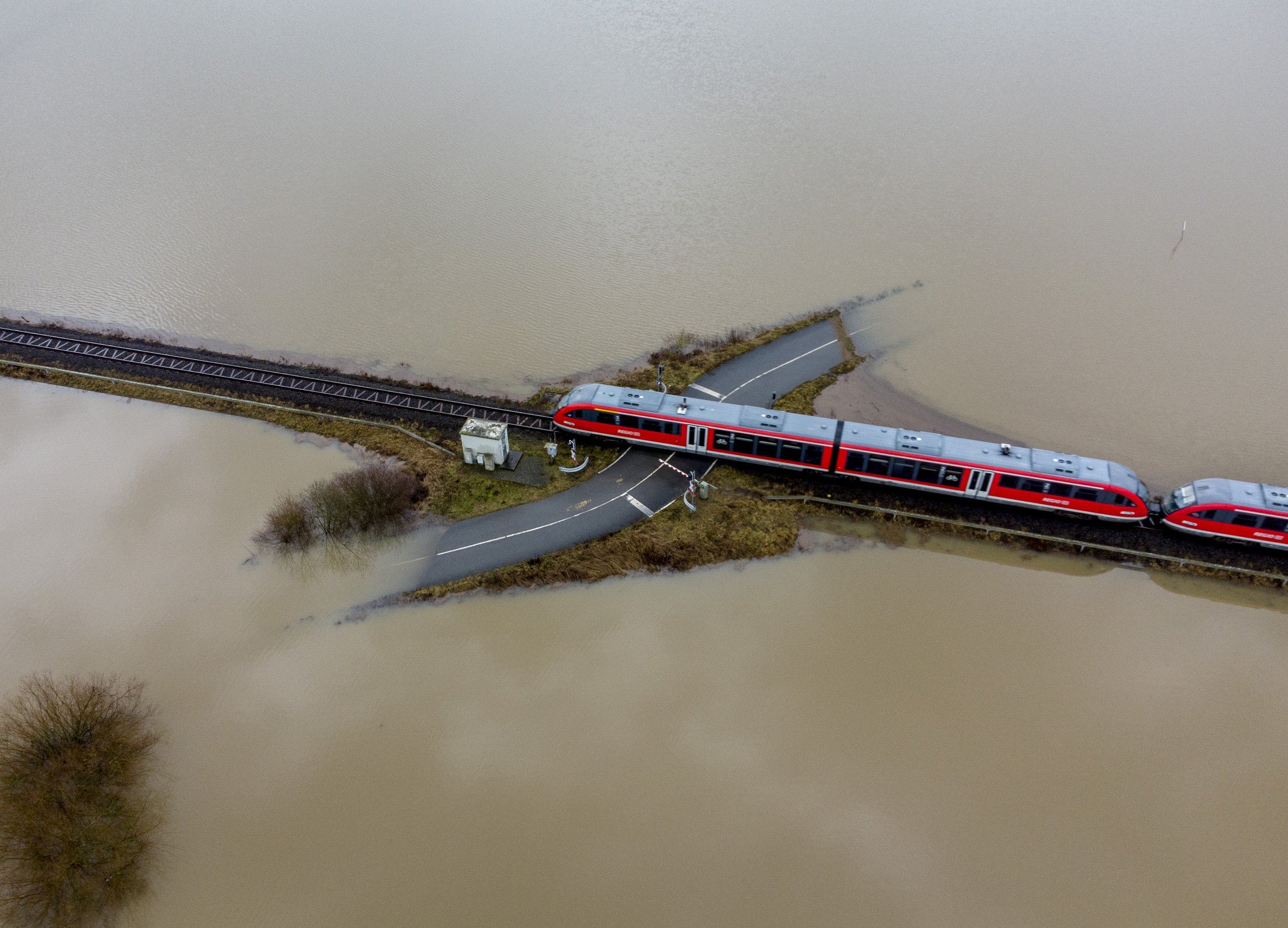  A train passes a railroad crossing that is surrounded by floodwaters from rain and melting snow in Nidderau near Frankfurt, Germany, on Feb. 3, 2021. (AP Photo/Michael Probst) 