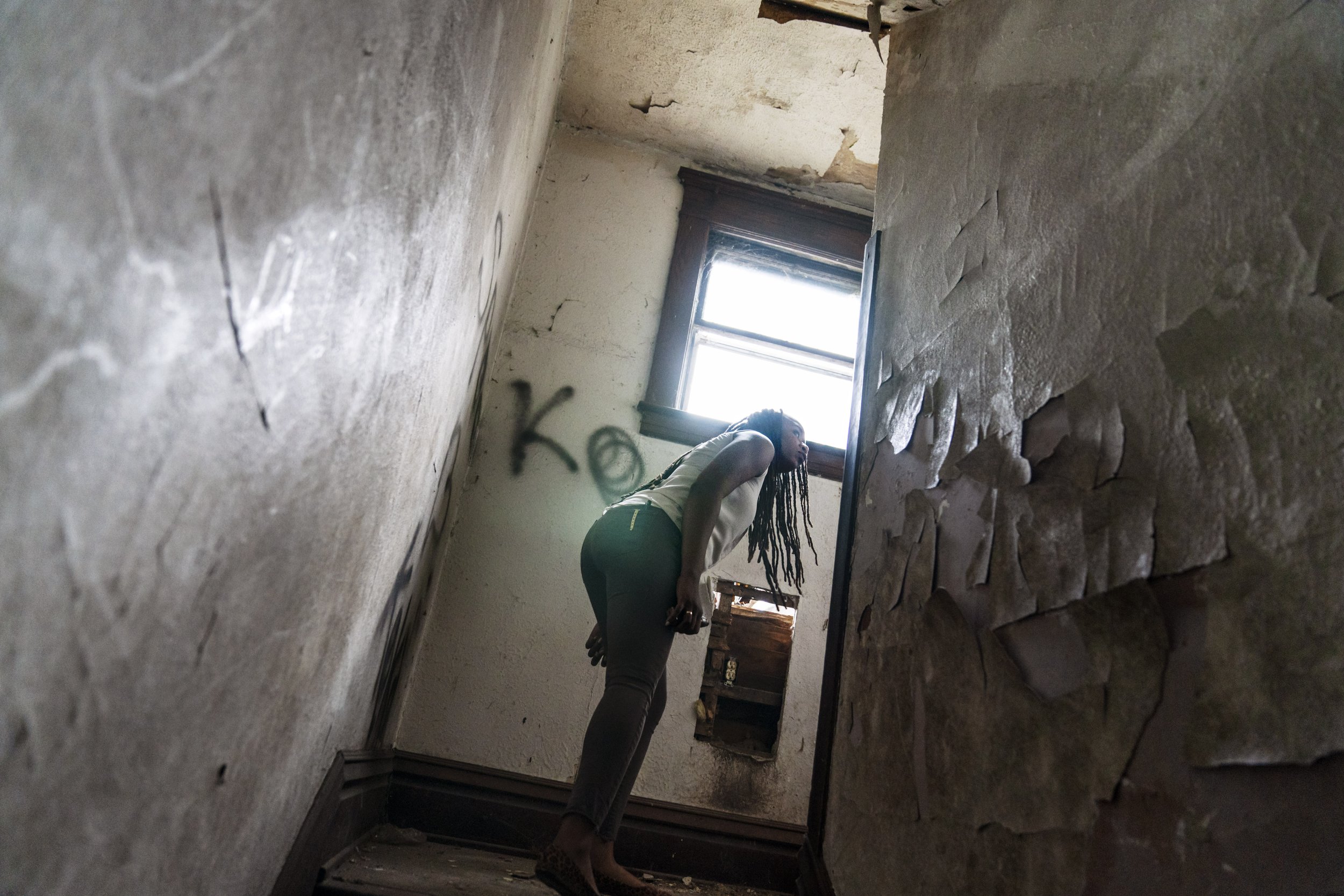  Larrecsa Cox peers around a stairwell while walking through an abandoned home frequented by people struggling with addiction, in Huntington, W.Va., on March 18, 2021. Cox leads the Quick Response Team, whose mission is to save every person who survi