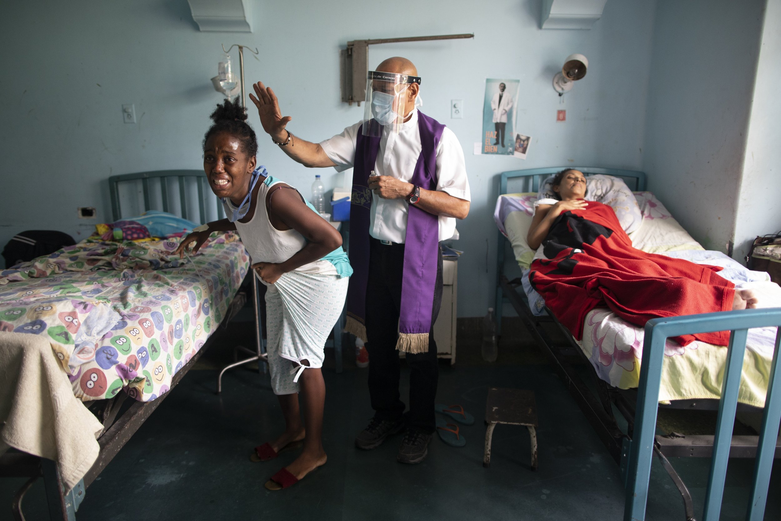  Father Felix Mendoza, a Venezuelan Catholic priest, prays over a woman who is crying from her physical pain, at a public hospital in Caracas, Venezuela, on May 11, 2021. (AP Photo/Ariana Cubillos) 