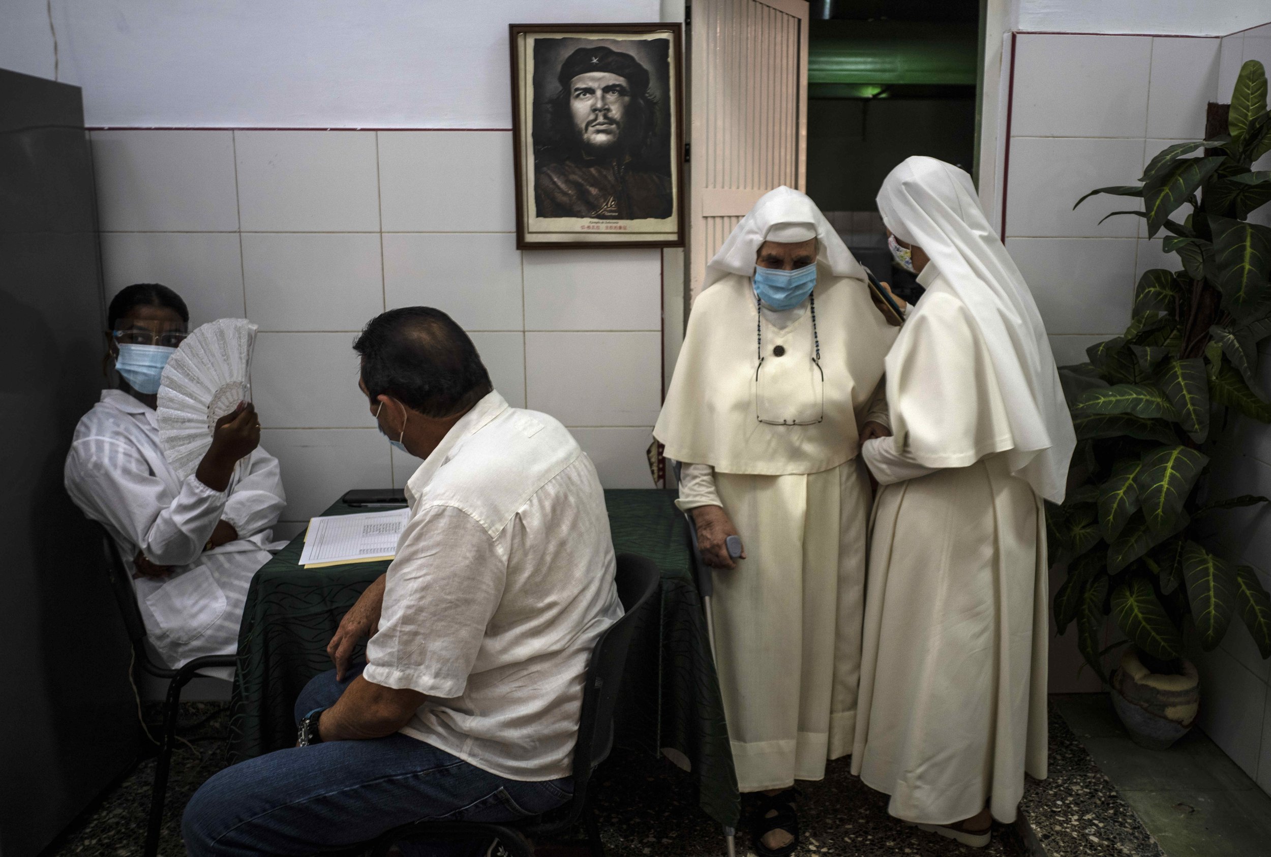  A framed image of Argentine-born Cuban Revolutionary hero Ernesto "Che" Guevara hangs on a wall as nuns leave after being inoculated with a dose of the Cuban Abdala COVID-19 vaccine, in Havana, Cuba, on June 23, 2021. (AP Photo/Ramon Espinosa) 