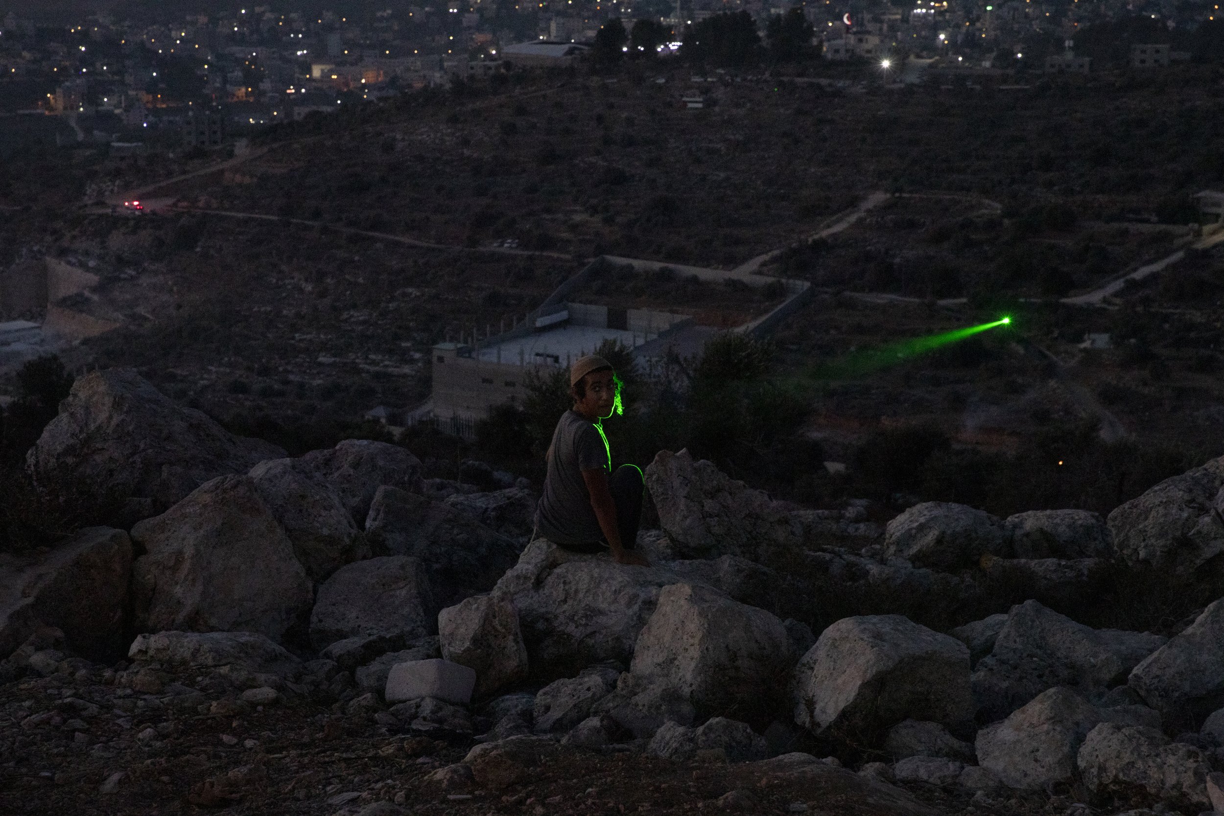 An Israeli settler is illuminated by a Palestinian protester’s laser at the recently established wildcat outpost of Eviatar near the West Bank city of Nablus, on July 1, 2021. (AP Photo/Maya Alleruzzo) 