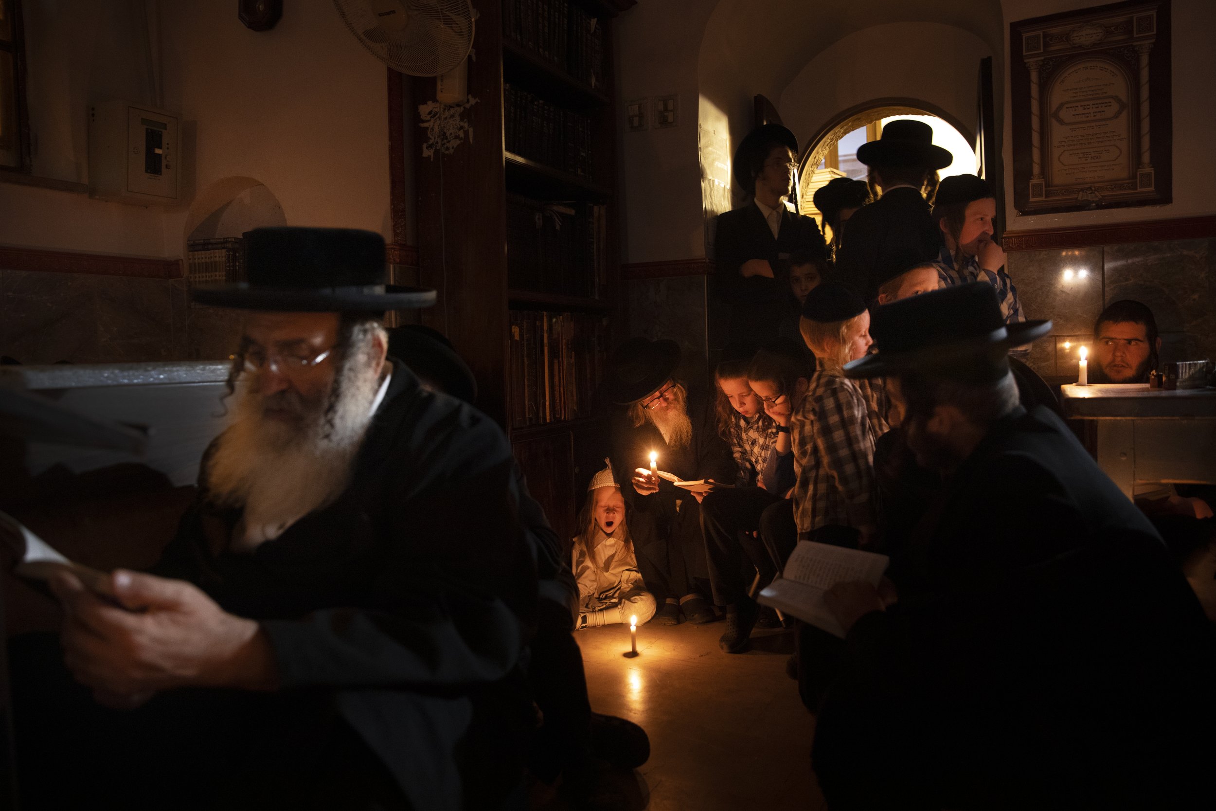  Ultra-Orthodox Jewish men and children read by candle light from the book of Eicha (Book of Lamentations) during the annual Tisha B'Av (Ninth of Av) fasting and memorial day, commemorating the destruction of ancient Jerusalem temples, in the Ultra-O