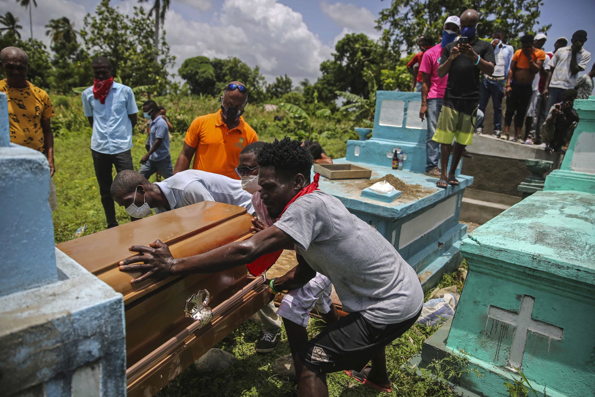  Men place a coffin containing the remains of Francois Elmay into a tomb after recovering his body from the rubble of a home destroyed four days earlier by a 7.2 magnitude earthquake in Tobek, Haiti, on Aug. 18, 2021. (AP Photo/Joseph Odelyn) 