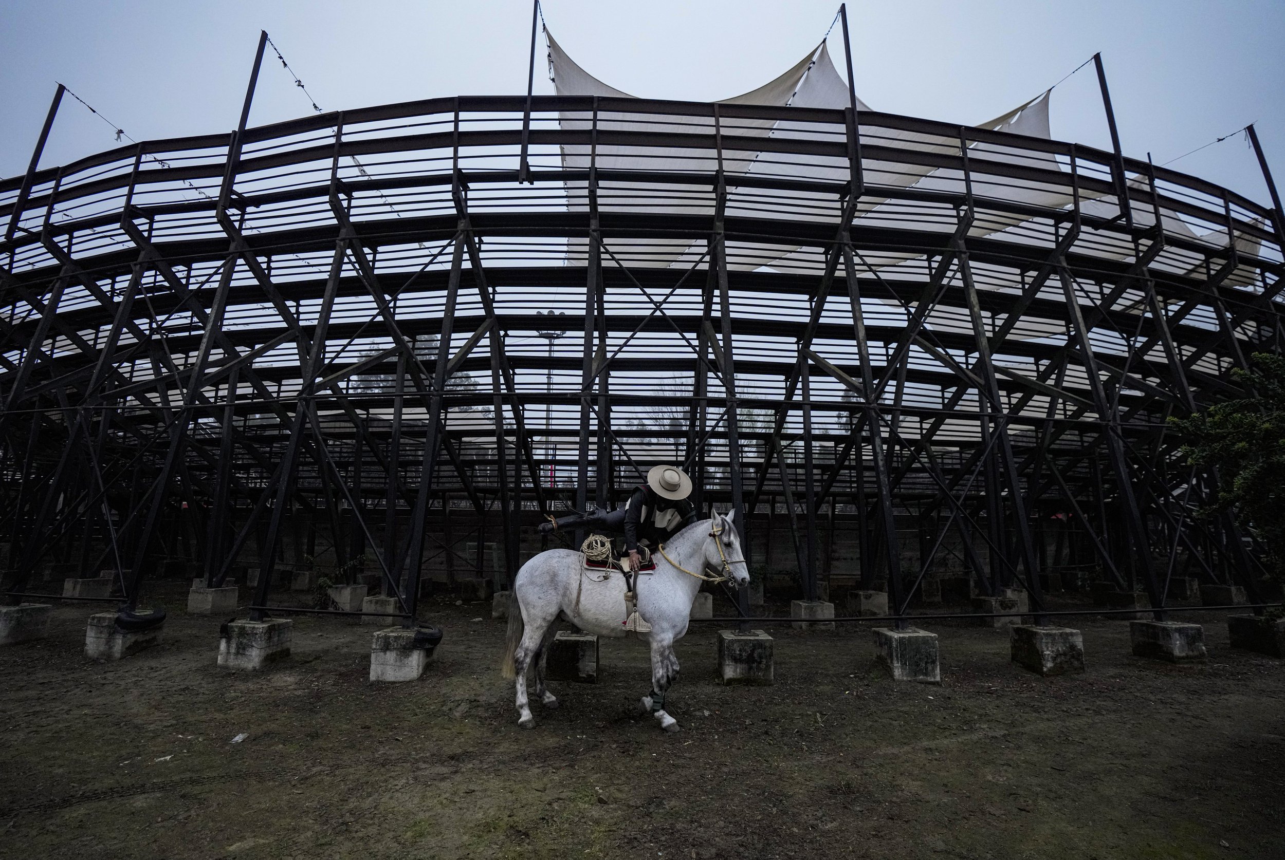  A Chilean horseback rider, or Huaso, mounts his horse under an arena empty of spectators due to restrictions related to the COVID-19 pandemic, at a traditional rodeo competition, a centerpiece of the country's Independence Day celebrations, in Melip