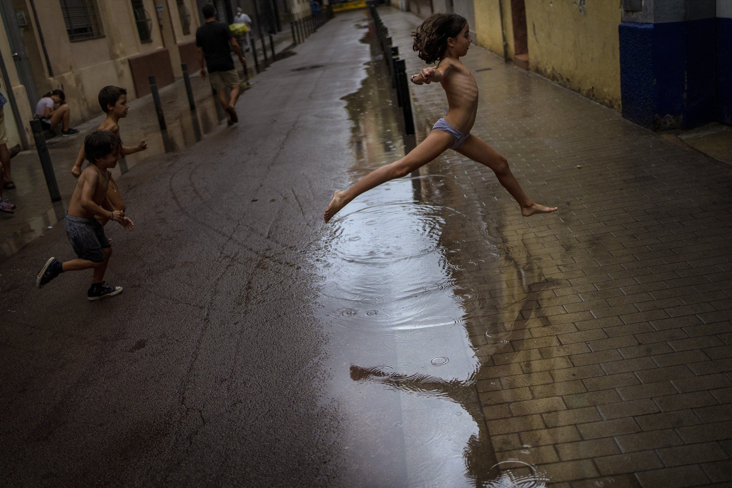  Children jump over a puddle of water as they play during a rainstorm on a street in Barcelona, Spain, on Sept. 18, 2021. (AP Photo/Emilio Morenatti) 