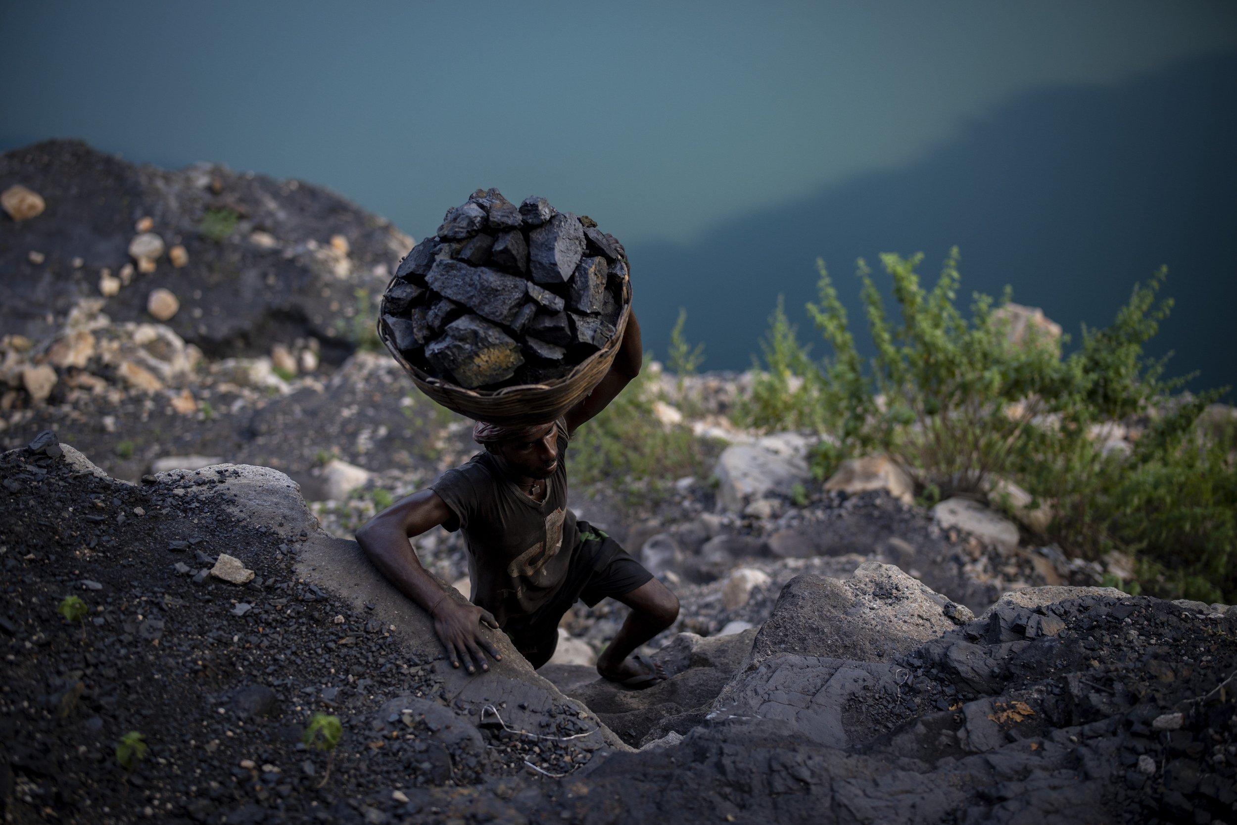  A man climbs a steep ridge with a basket of coal scavenged from a mine near Dhanbad, India, in the eastern state of Jharkhand, on Sept. 24, 2021. A 2021 Indian government study found that Jharkhand state, among the poorest in India and the state wit