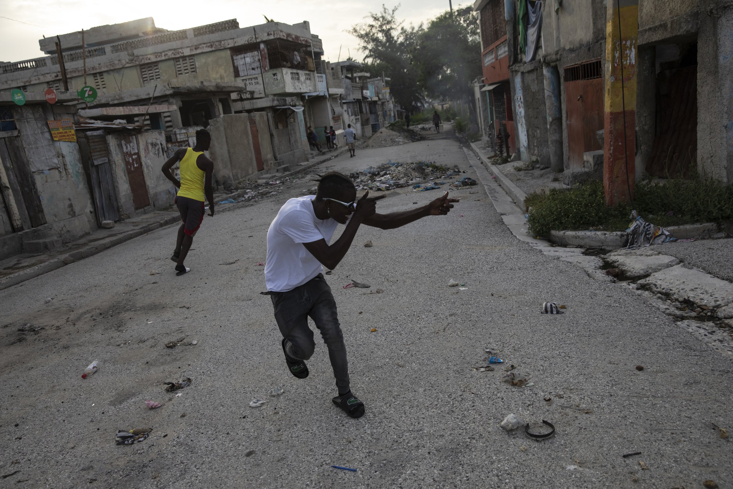  A gang member points an imaginary weapon at a rival gang on a corner that divides control of two gangs in the Bel Air neighborhood of Port-au-Prince, Haiti, on Oct. 5, 2021. (AP Photo/Rodrigo Abd) 