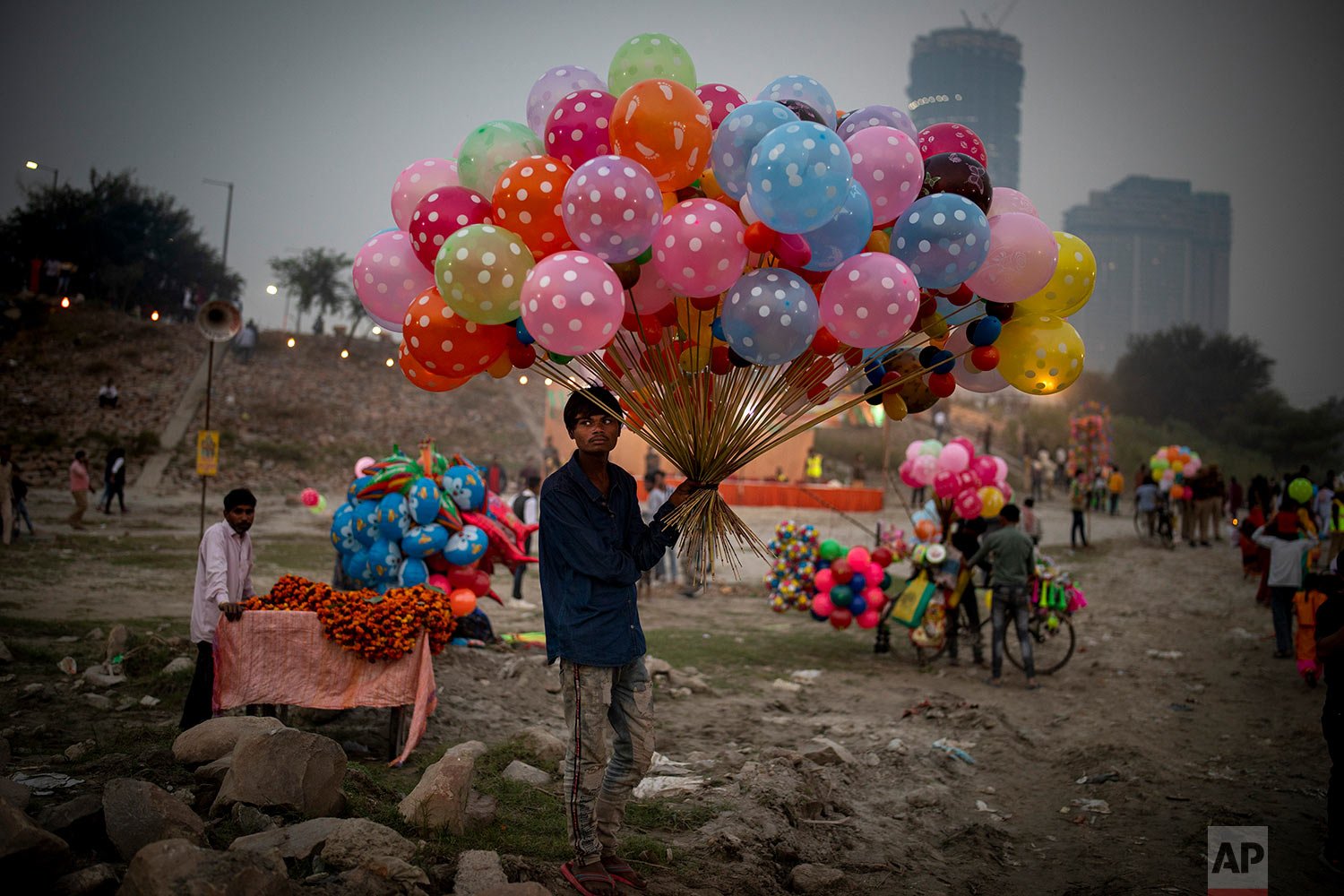  A balloon seller waits for customers on the banks of Yamuna river during Chhath Puja festival in New Delhi, India, Wednesday, Nov. 10, 2021. (AP Photo/Altaf Qadri) 
