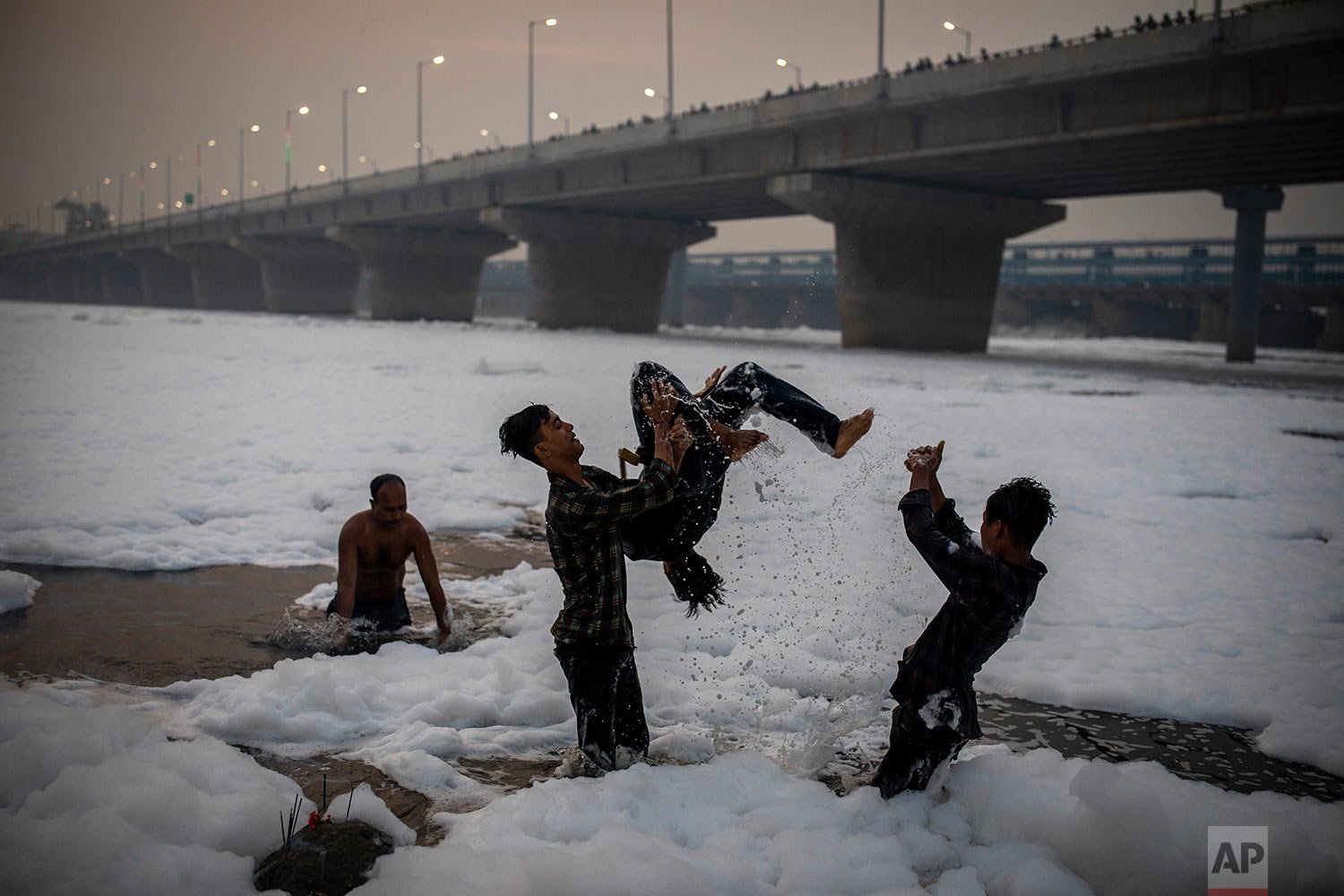  Young Hindu devotees play in Yamuna river, covered by chemical foam caused due to industrial and domestic pollution, during Chhath Puja festival in New Delhi, India, Wednesday, Nov. 10, 2021. (AP Photo/Altaf Qadri) 