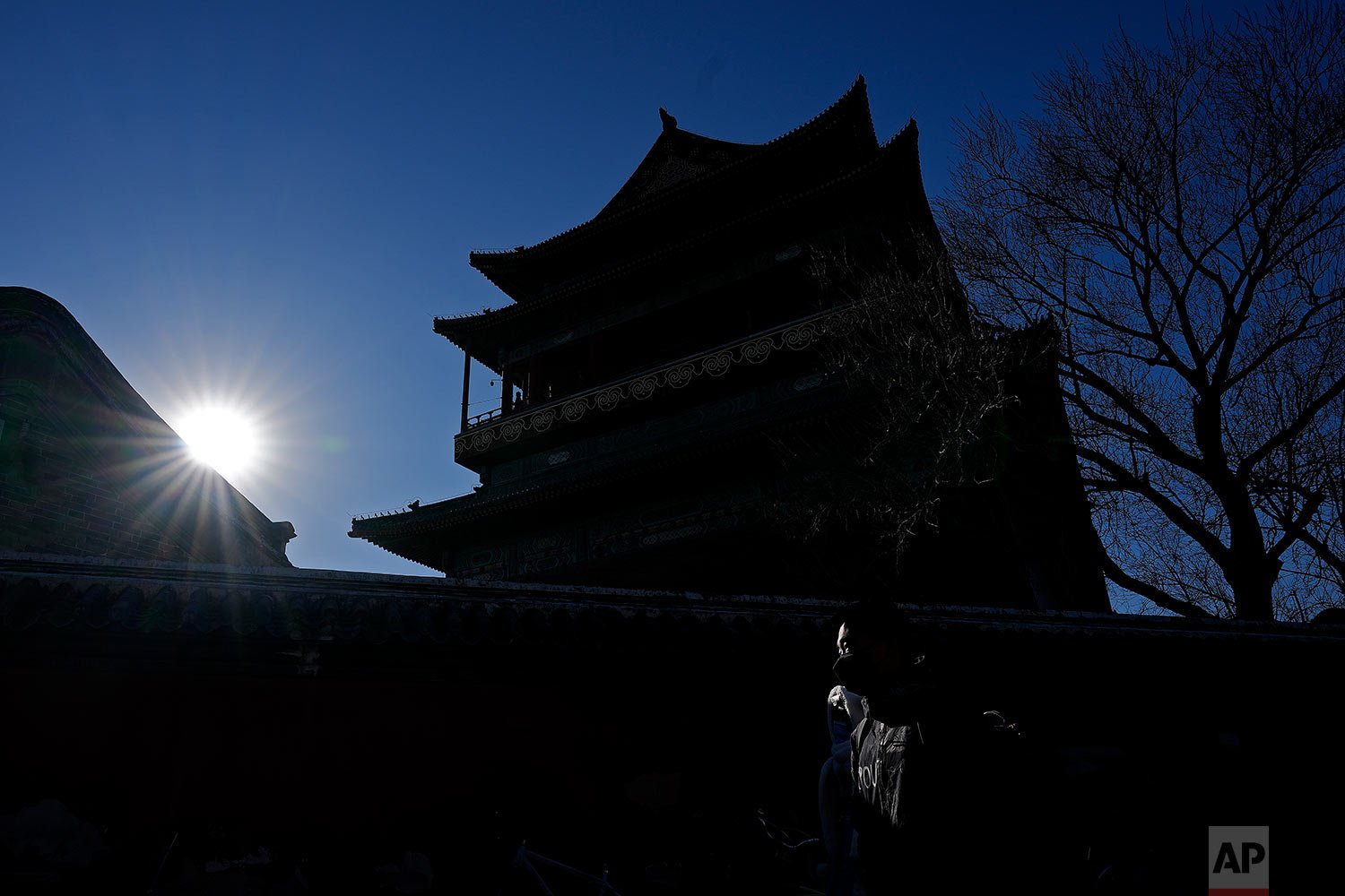  A beam of sunlight is cast on a couple  as they walk by the drum tower, a tourist attraction in Beijing, Monday, Nov. 22, 2021. (AP Photo/Andy Wong) 