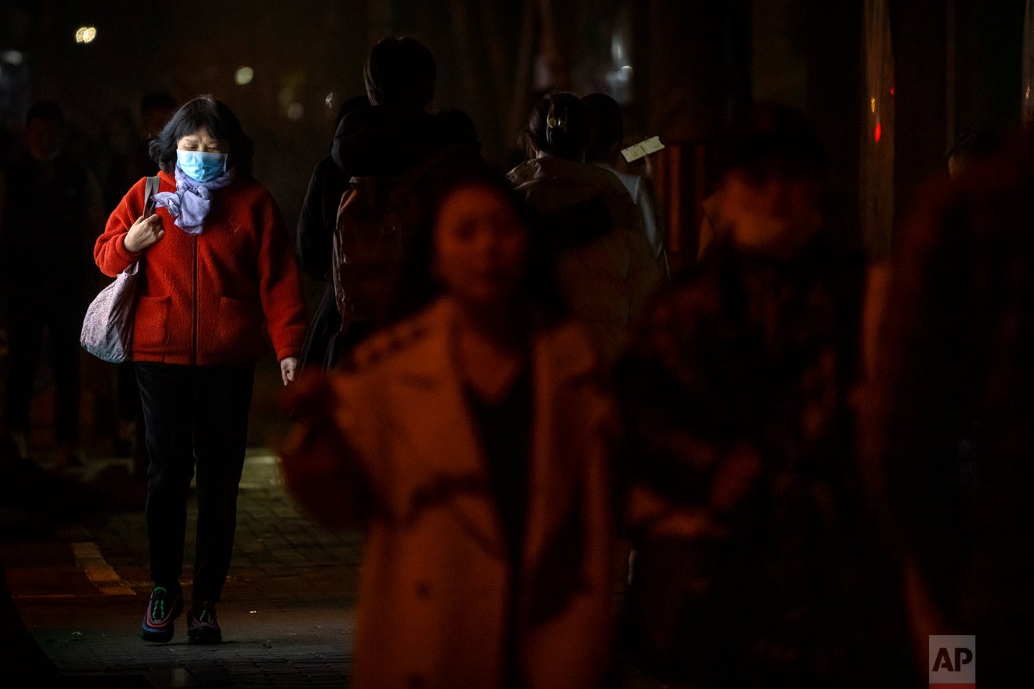  A woman wearing a face mask to protect against COVID-19 walks past a lit advertising billboard along a street in Beijing, Friday, Nov. 5, 2021. (AP Photo/Mark Schiefelbein) 