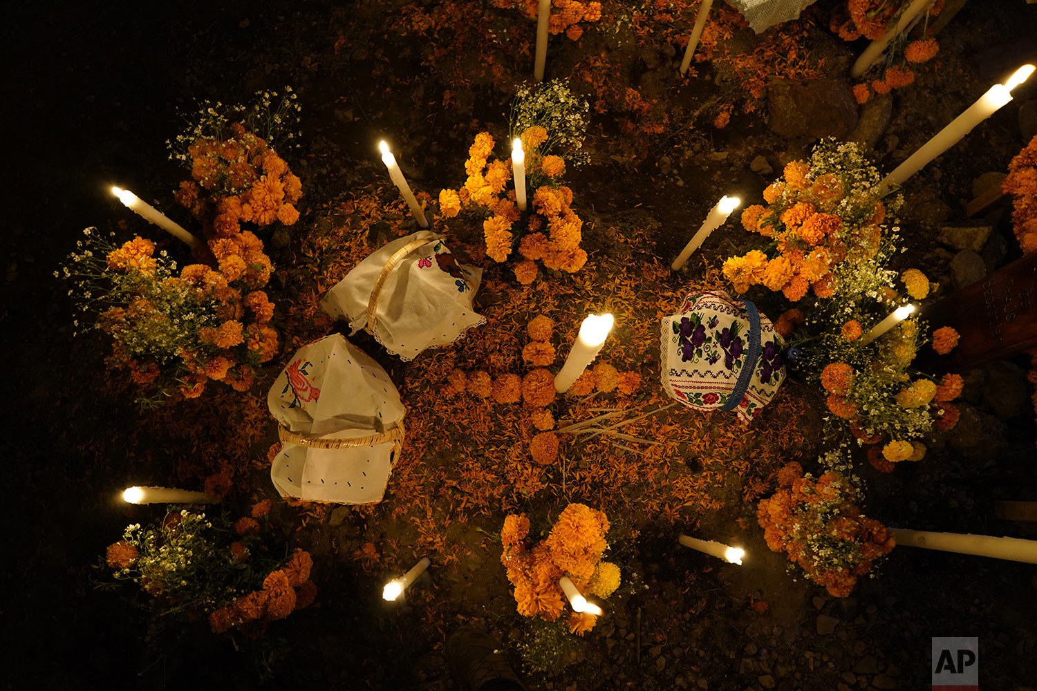  Flowers, food offerings and candles adorn a tomb as relatives spend the night next to the tomb of their loved one during Day of the Dead festivities at the the Arocutin cemetery in Michoacan state, Mexico, Nov. 1, 2021. (AP Photo/Eduardo Verdugo) 