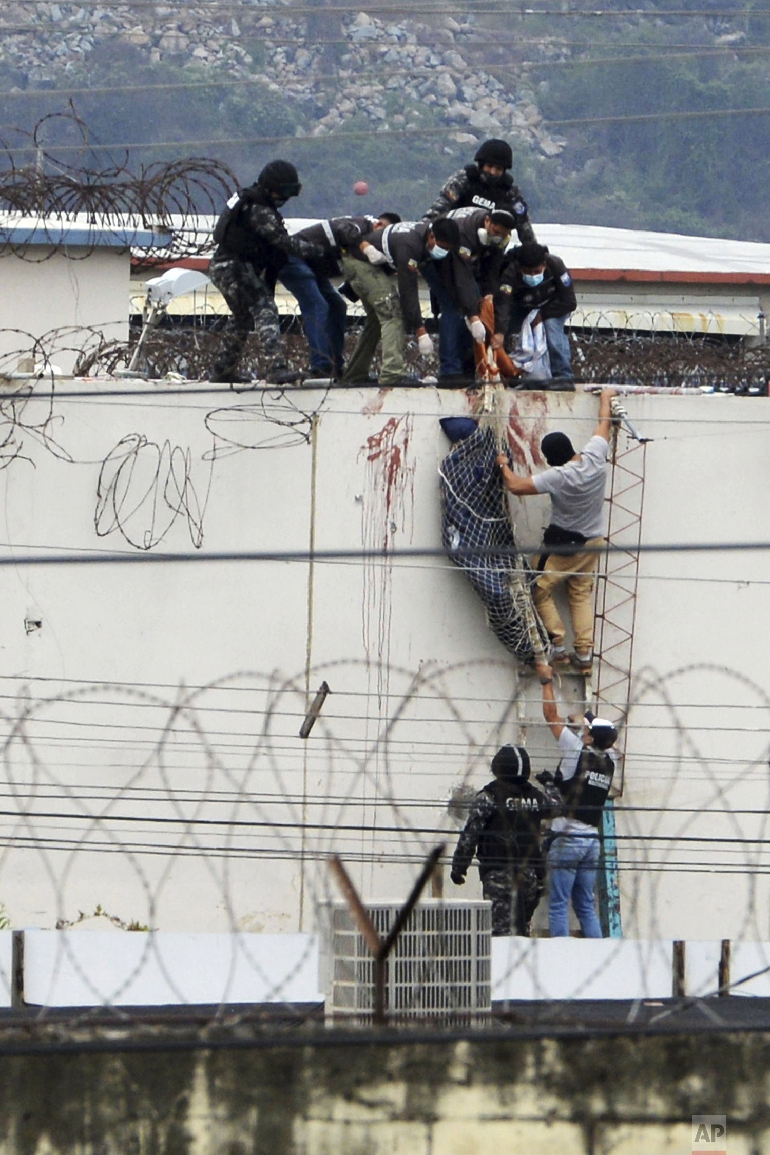  Police lower the body of a prisoner from the roof of the Litoral penitentiary the morning after riots broke out inside the jail in Guayaquil, Ecuador, Nov. 13, 2021. (AP Photo/Jose Sanchez) 