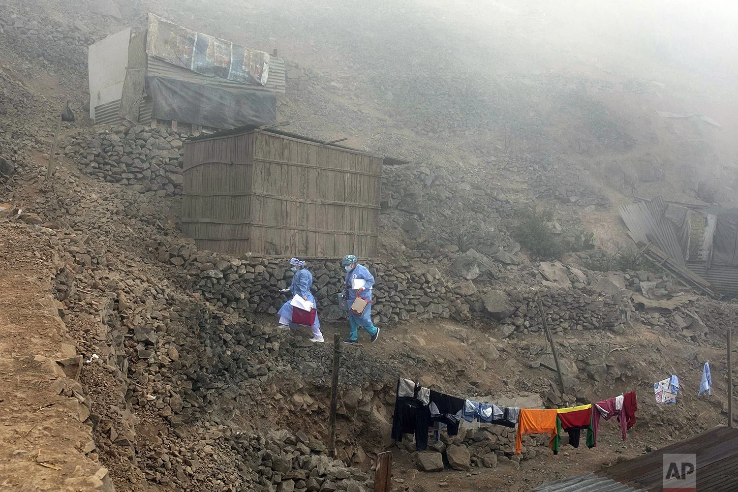 Healthcare workers carry coolers filled with doses of the Pfizer COVID-19 vaccine, during a door-to-door vaccination campaign in the Villa Maria del Triunfo district, on the outskirts of Lima, Peru, Nov. 16, 2021. (AP Photo/Guadalupe Pardo)