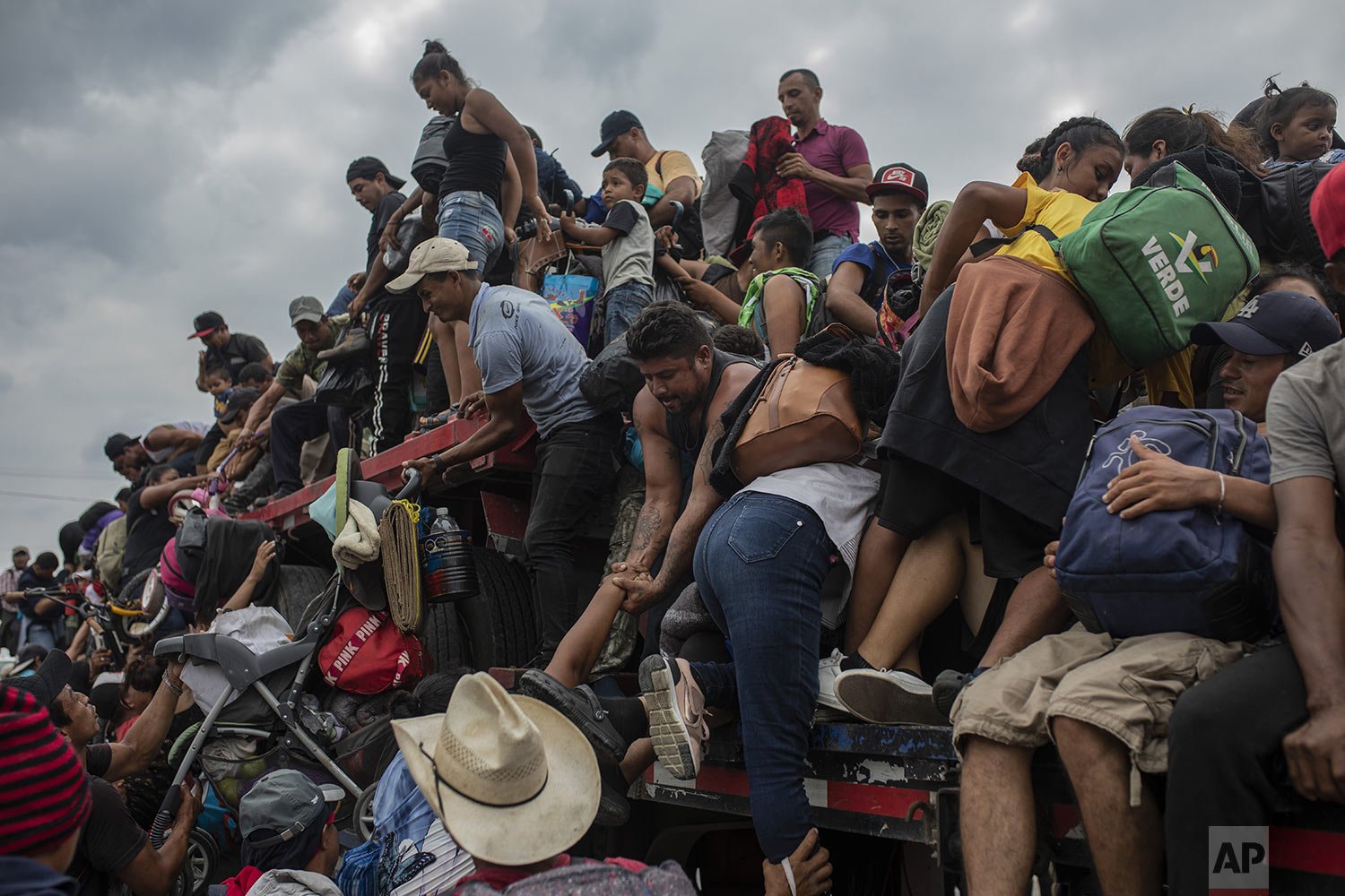  Migrants, who are part of a caravan of mainly Central Americans attempting to reach the U.S.-Mexico border, help fellow migrants onto the bed of a trailer in Jesus Carranza, in the Mexican state of Veracruz, Nov. 17, 2021. (AP Photo/Felix Marquez) 