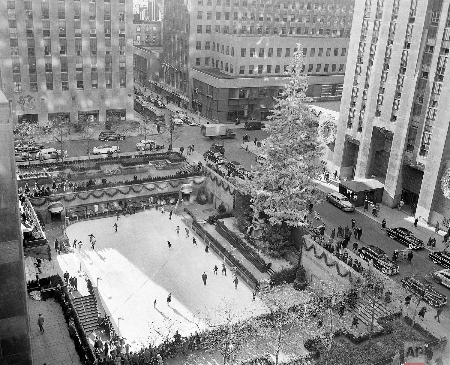  With the famed Rockefeller Center Christmas tree rising above them, skaters glide on the ice at the center's skating rink in midtown Manhattan, New York, Dec. 8, 1949. (AP Photo/John Lindsay) 