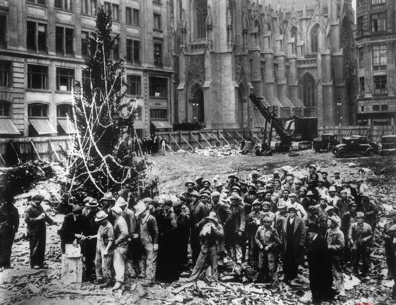  Construction workers line up for pay beside the first Rockefeller Center Christmas tree in New York in 1931.  The Christmas tree went on to become an annual tradition and a New York landmark.  St. Patrick's Cathedral is visible in the background on 