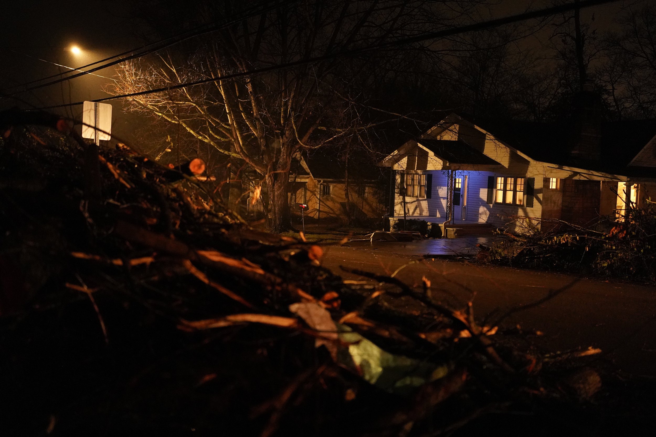  A home in Bowling Green, Ky., is illuminated by a street light and surrounded by tree branches and other debris on Friday, Dec. 17, 2021. (AP Photo/Brynn Anderson) 