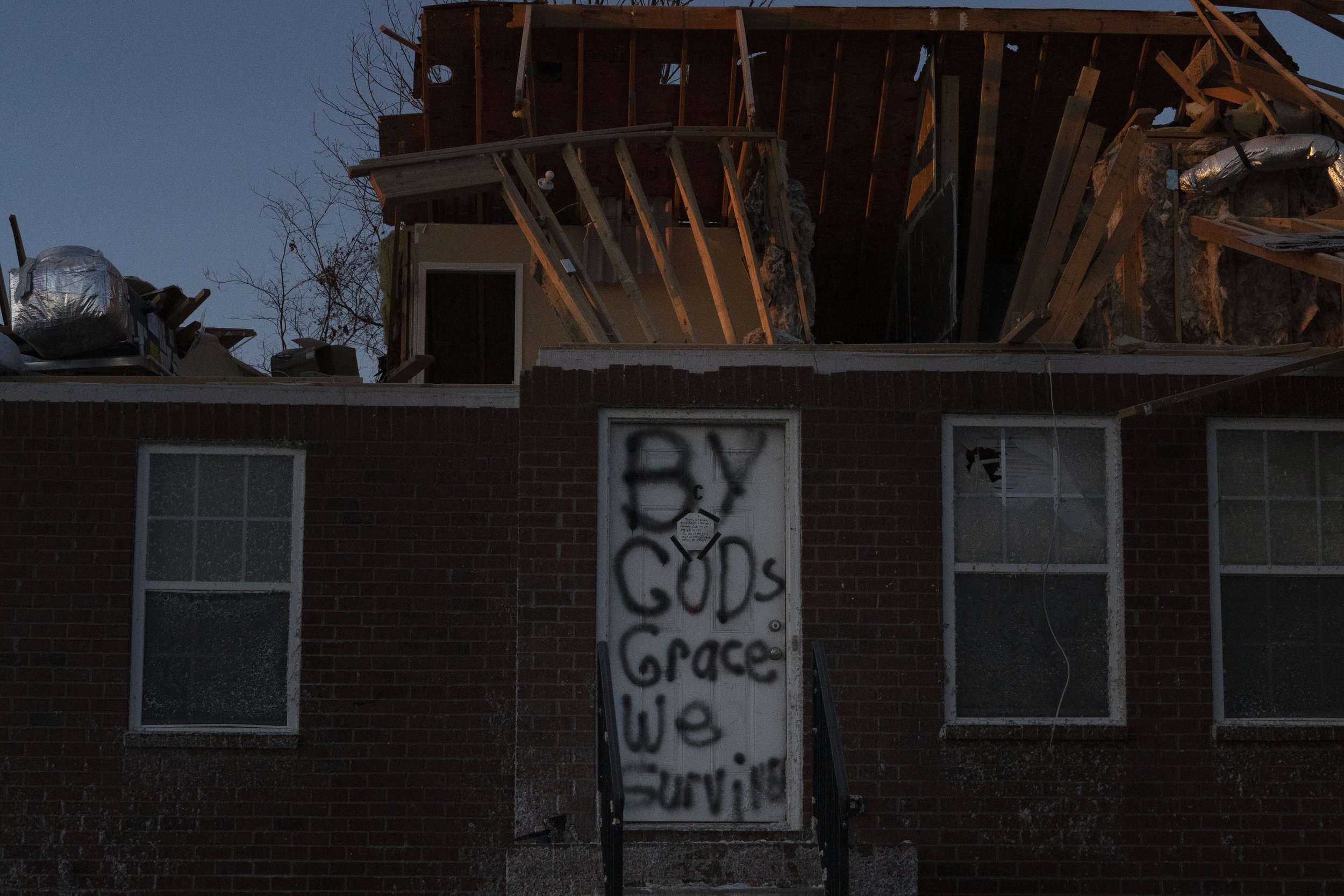  A door is spray painted with the message "By Gods Grace We Survive" on Dec. 20, 2021, following the tornado that ripped through Bowling Green, Ky. (AP Photo/Brynn Anderson) 