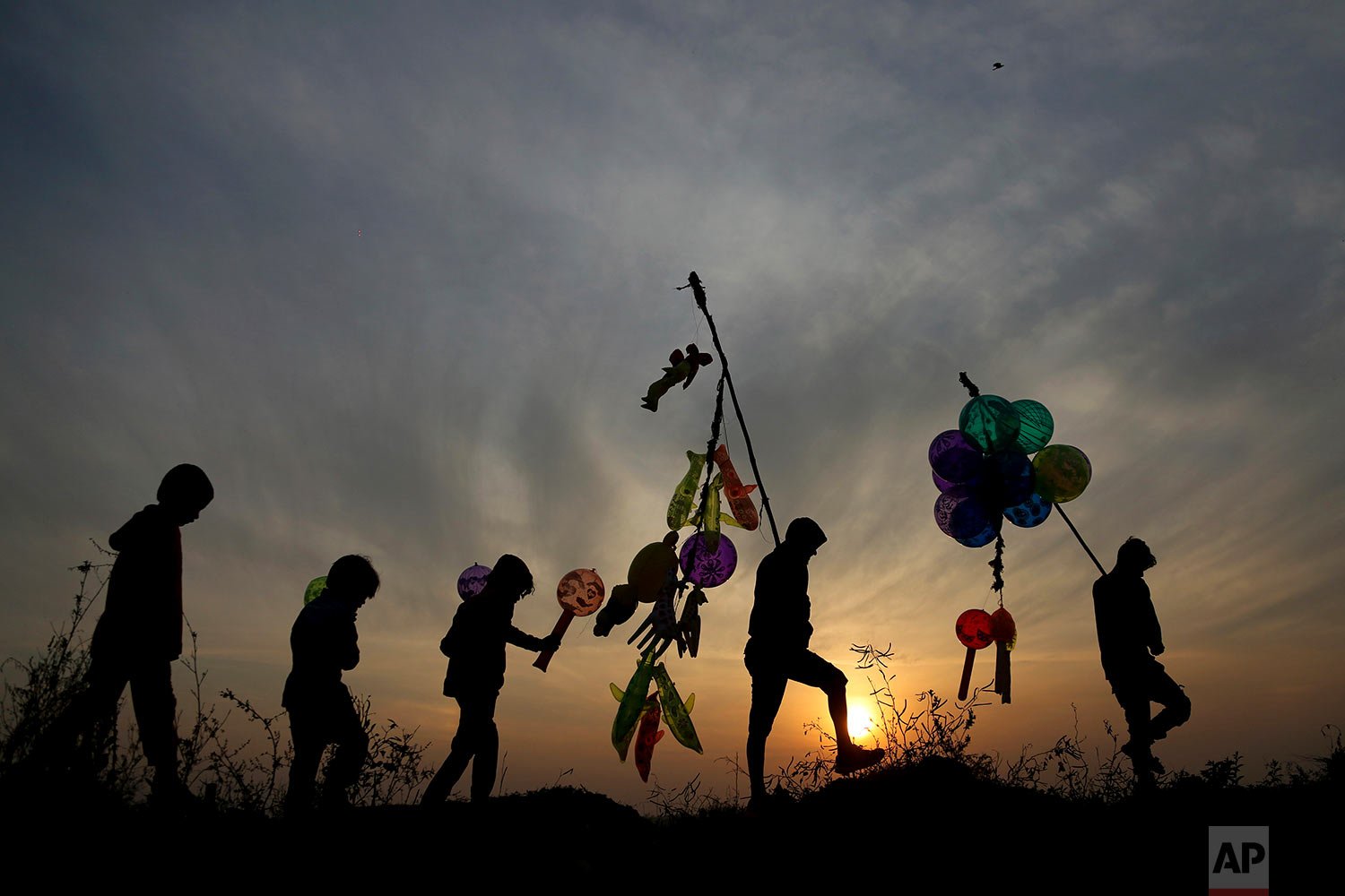  Indian balloon vendors walk back home as the sun sets on New Year's Eve in Jammu, India, Friday, Dec. 31, 2021. (AP Photo/Channi Anand) 
