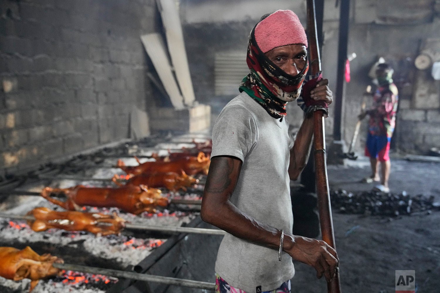  A worker wearing a mask to prevent the spread of the coronavirus cooks roasted pigs in Manila, Philippines on Christmas Eve, Friday, Dec. 24, 2021.  (AP Photo/Aaron Favila) 