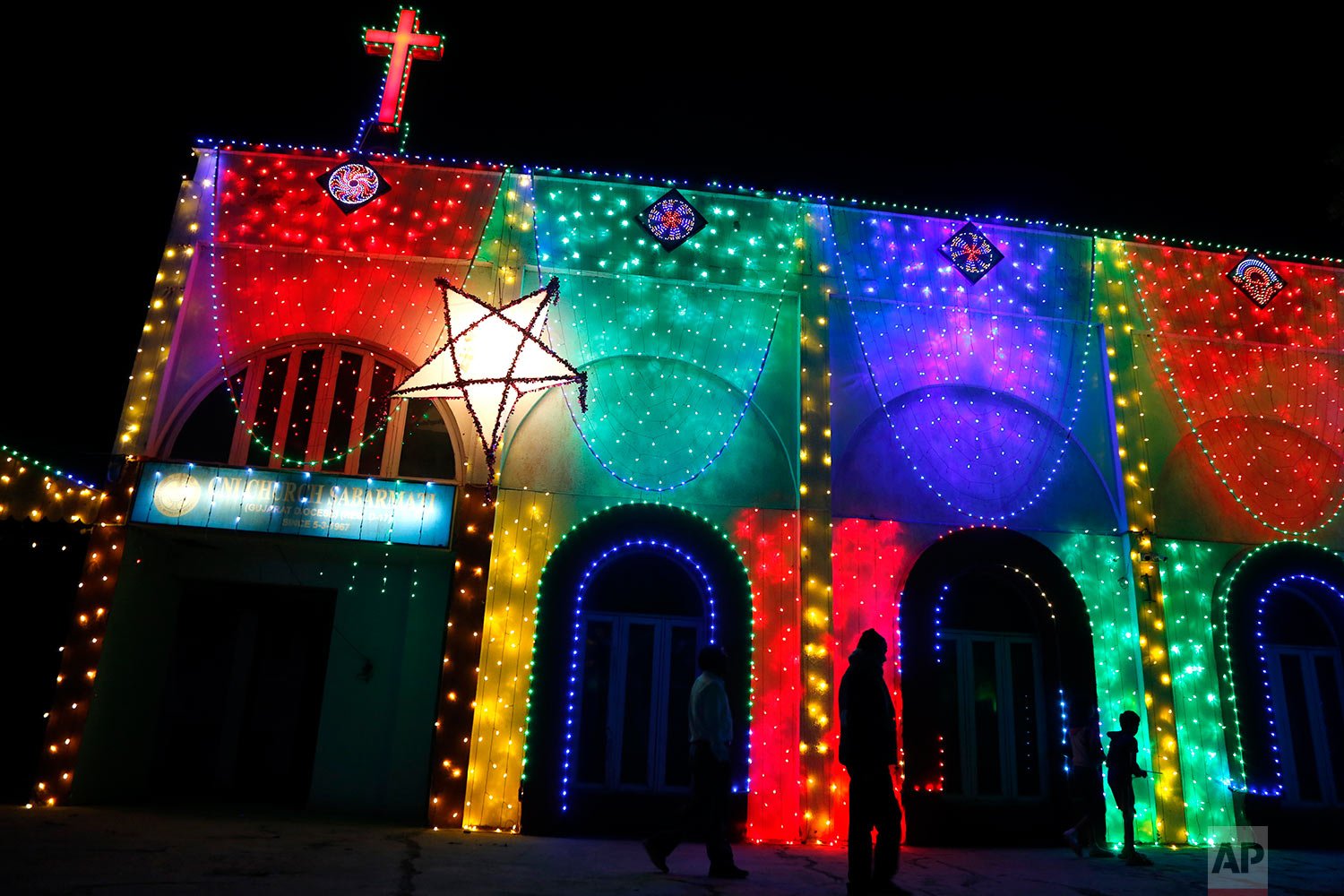  People walk past an illuminated church ahead of Christmas in Ahmedabad, India, Wednesday, Dec. 22, 2021. (AP Photo/Ajit Solanki) 