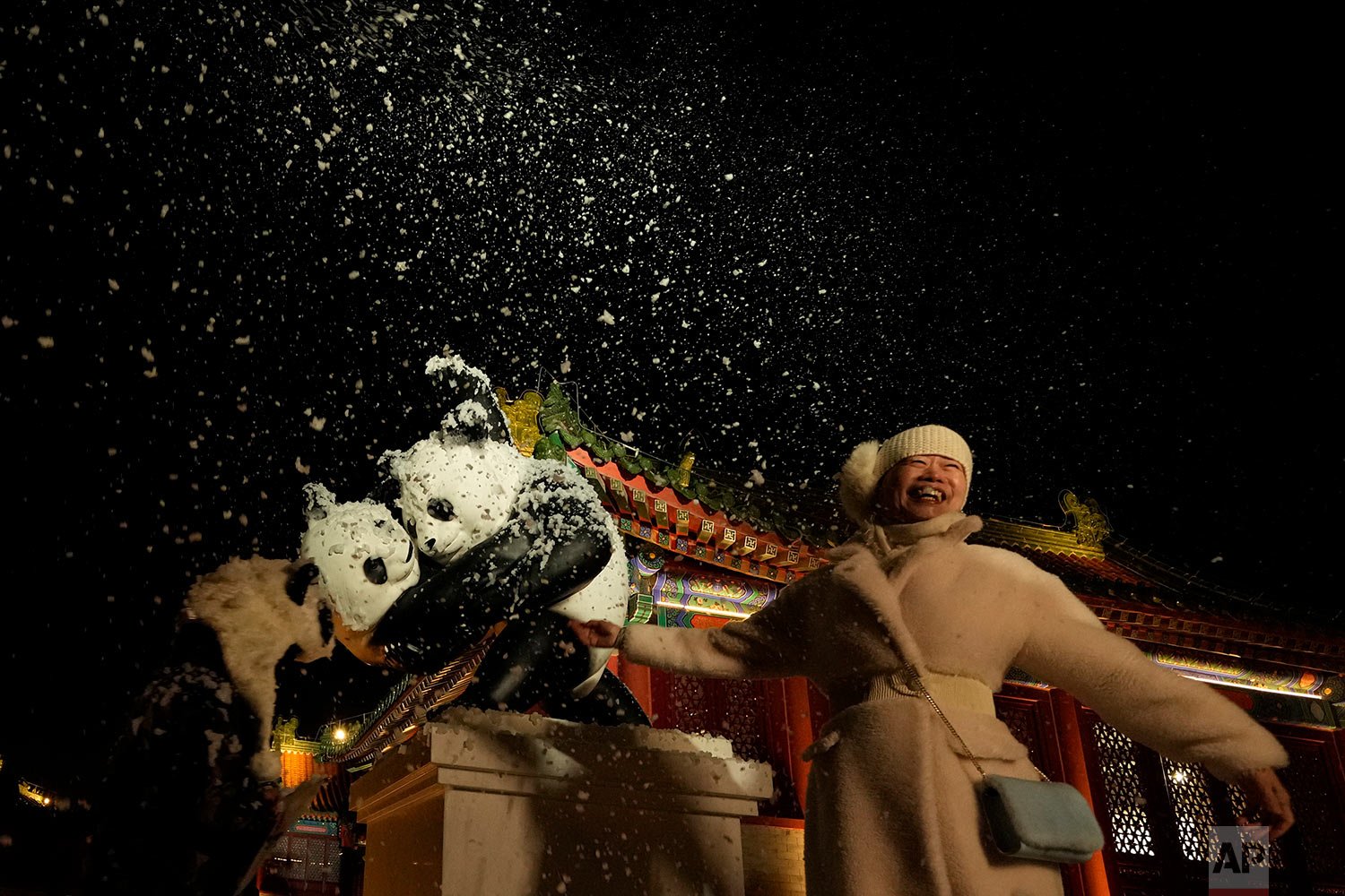  An attendee at an event that coincided with the New Year Eve smiles as fake snow from a foam machine is blown overhead in Beijing, China, Friday, Dec. 31, 2021. (AP Photo/Ng Han Guan) 