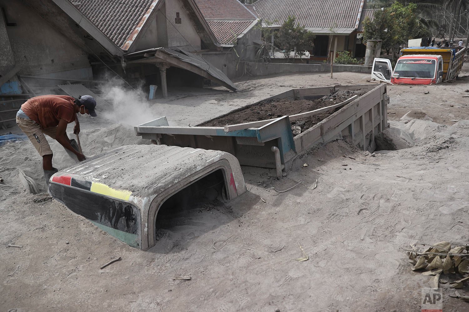  A man inspects a truck buried in the ash following the eruption of Mount Semeru in Lumajang district, East Java province, Indonesia, Sunday, Dec. 5, 2021. (AP Photo/Trisnadi) 