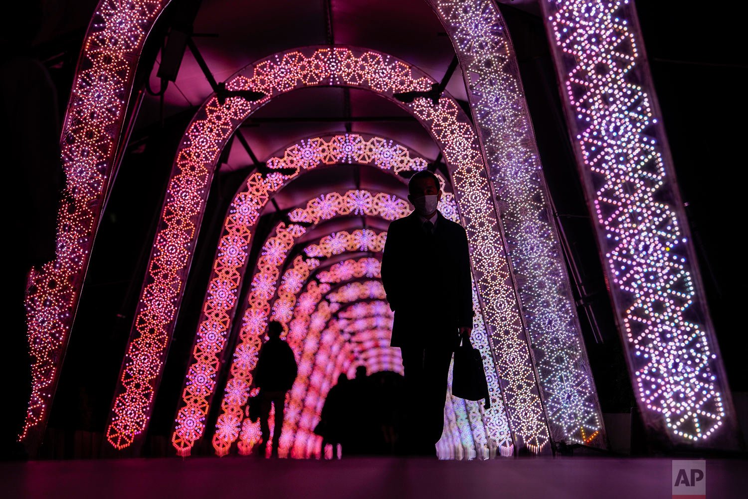  People walk through a tunnel of a holiday light display Thursday, Dec. 9, 2021, in Tokyo. (AP Photo/Kiichiro Sato) 