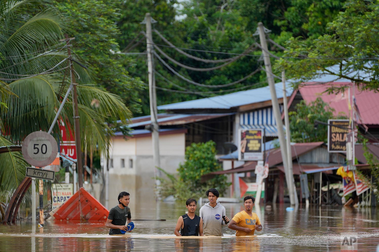  People wade through a flooded road in Hulu Langat, outside Kuala Lumpur, Malaysia, Sunday, Dec. 19, 2021.  (AP Photo/Vincent Thian) 