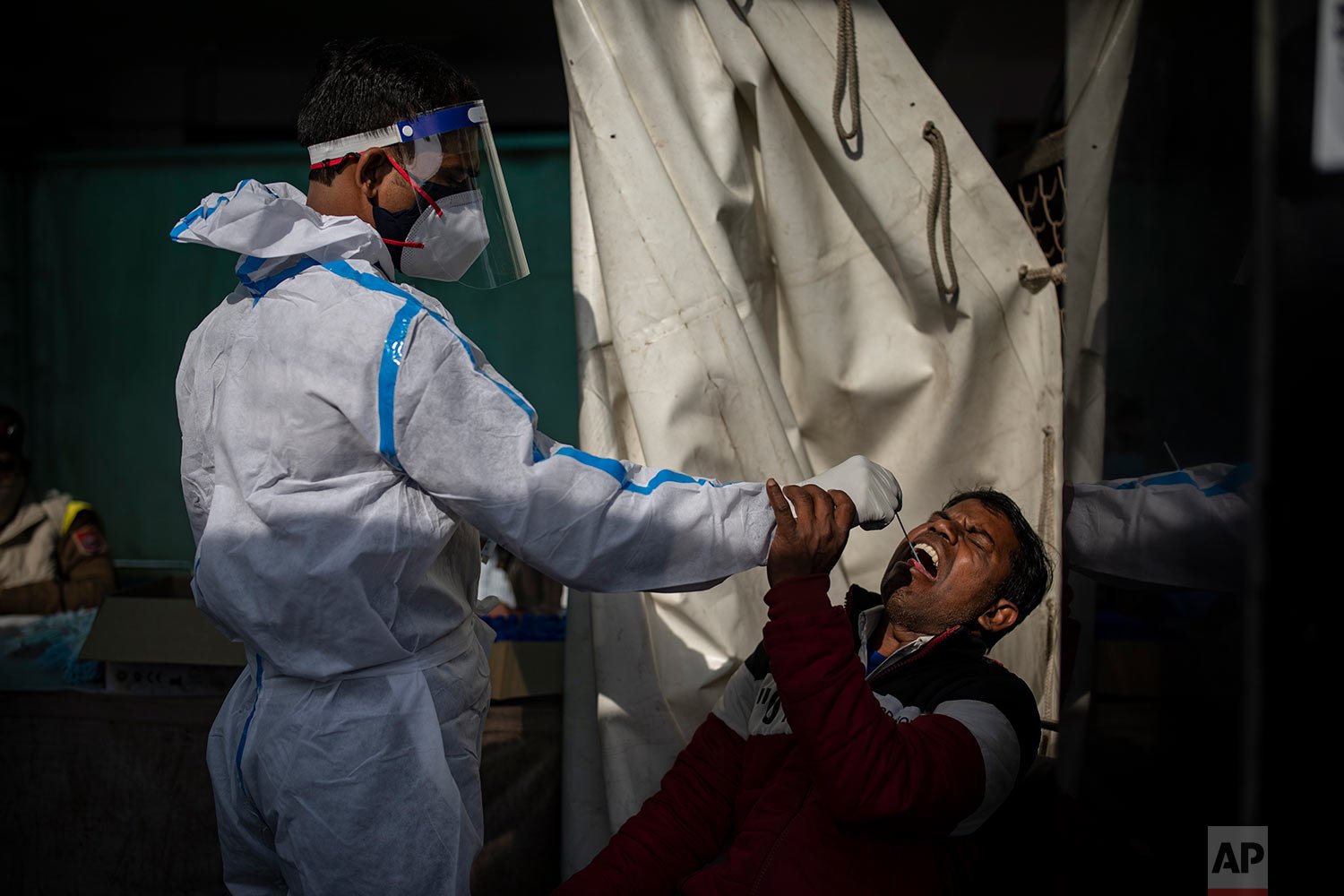  A health worker collects a swab sample of a passenger to test for COVID-19 at a train station in New Delhi, India, Thursday, Dec. 30, 2021.  (AP Photo/Altaf Qadri) 