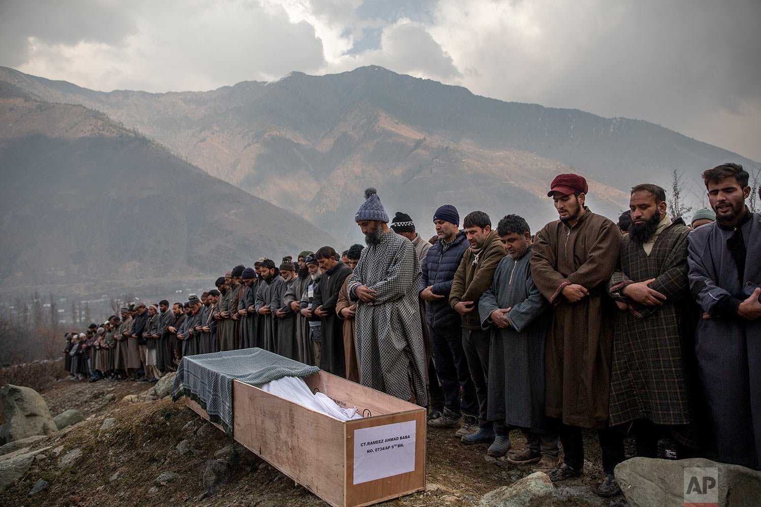  Relatives and neighbors pray by the body of Rameez Ahmad, a policeman who was killed in Monday's gun attack, during his funeral in Yachama, northeast of Srinagar, Indian controlled Kashmir, Tuesday, Dec. 14, 2021. (AP Photo/Dar Yasin) 