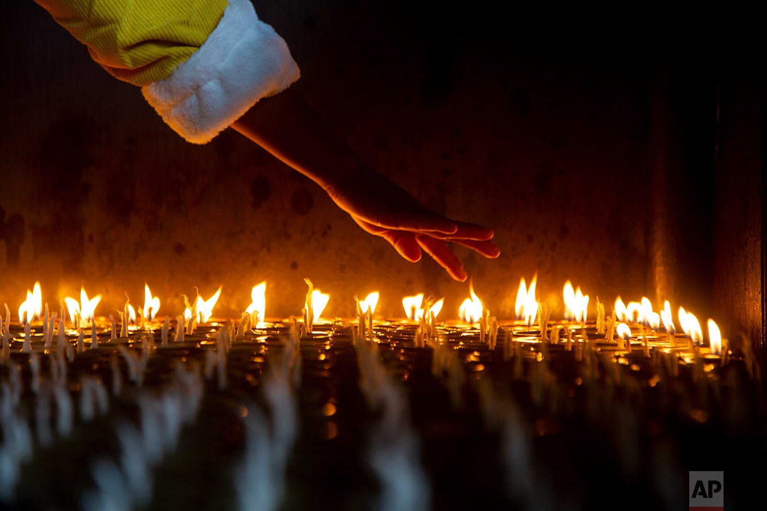  A Nepalese devotee counts butter lamps before she lights them at the Boudhanath Stupa in Kathmandu, Nepal, Monday, Dec. 27, 2021. (AP Photo/Niranjan Shrestha) 
