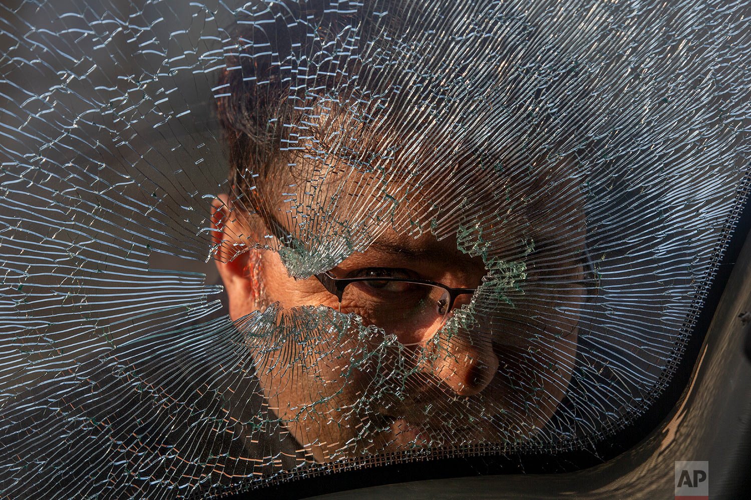  A Kashmiri man looks through the broken glass of a parked vehicle near the site of a shootout on the outskirts of Srinagar, Indian controlled Kashmir, Friday, Dec. 31, 2021.  (AP Photo/Dar Yasin) 