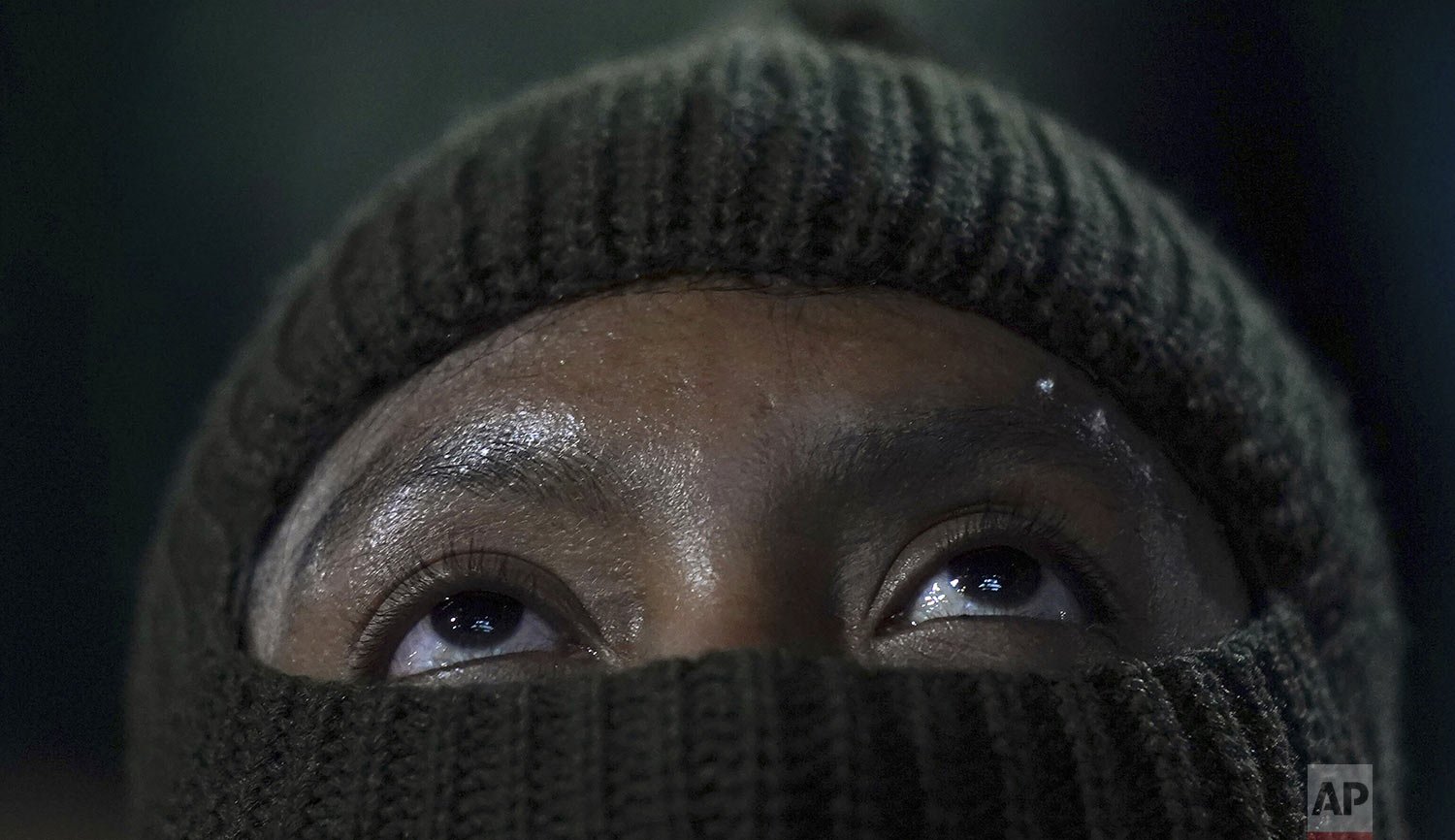  A Honduran migrant who is part of a caravan that is slowly moving north looks up during a protest outside of the National Institute of Migration headquarters in Mexico City, Dec. 14, 2021. The demonstration was to protest the rough treatment they sa