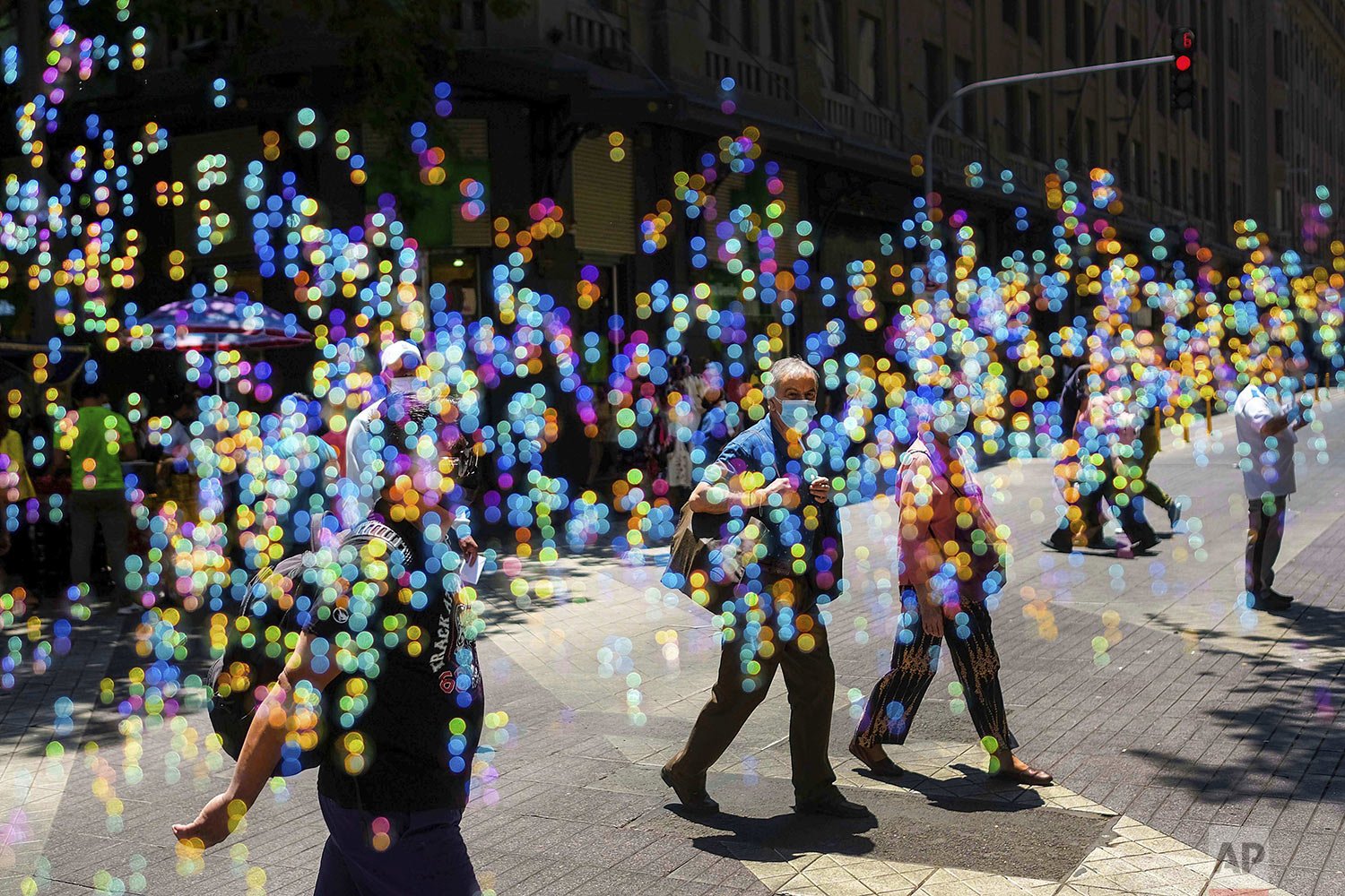  People cross a street amid soap bubbles in downtown Santiago, Chile, Dec. 3, 2021. (AP Photo/Matias Delacroix) 