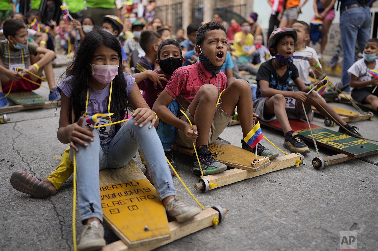  Children compete in a traditional street race of "carruchas," the name for makeshift wooden cars in Caracas, Venezuela, Dec. 18, 2021. (AP Photo/Ariana Cubillos) 