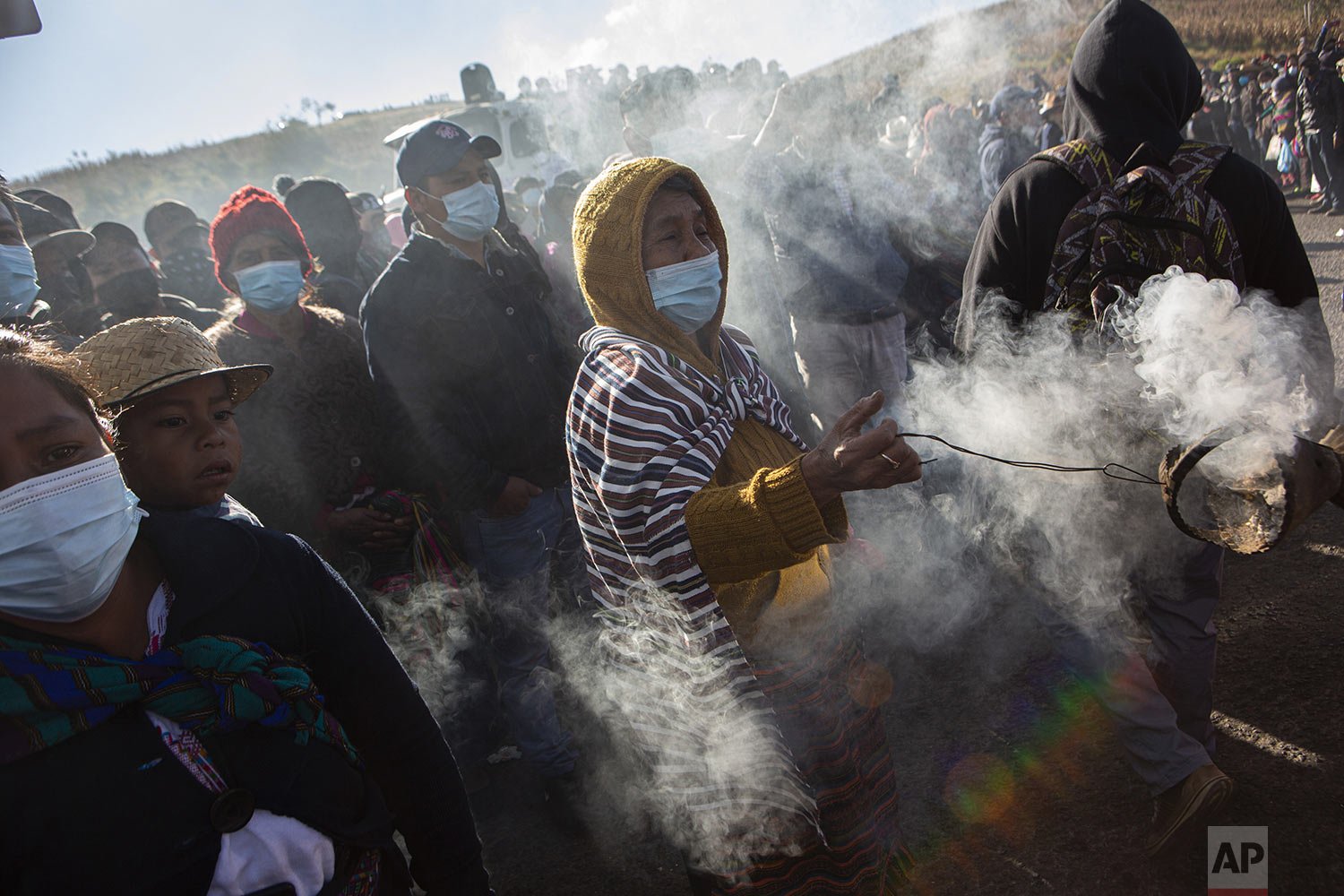  A woman spreads incense as coffins are brought to a protest against violence in Santa Catarina Ixtahuacan, Guatemala, Dec. 20, 2021. A dozen people were slain in Chiquix, a village that has been involved in a years-long territorial dispute with Sant