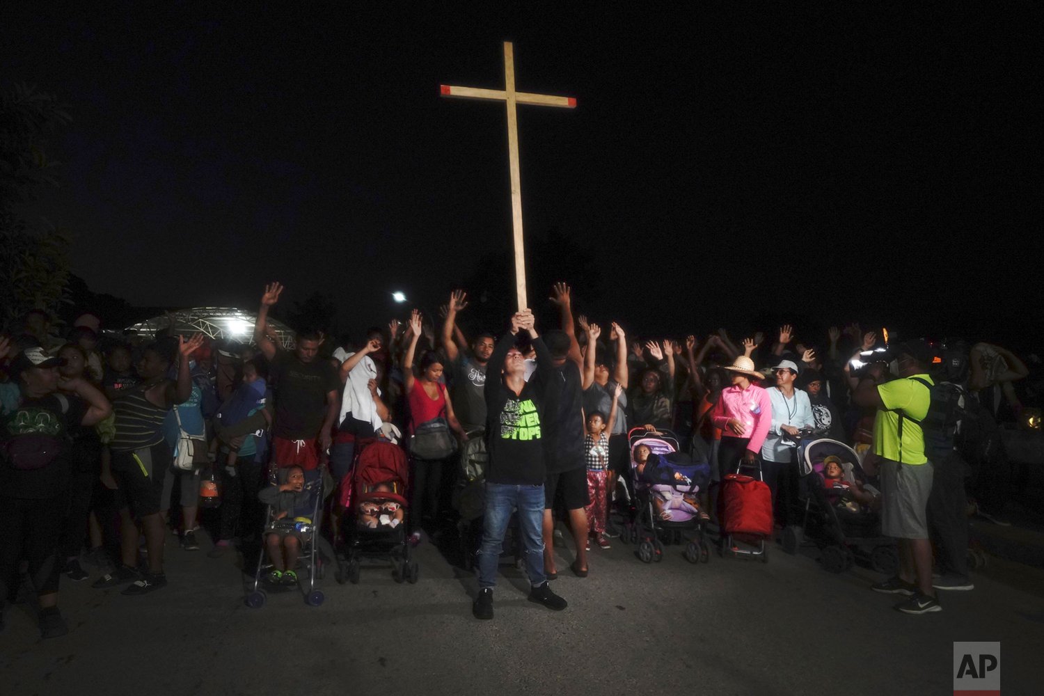  A migrant holds up a cross at the front of a migrant group leaving Huixtla by foot in Chiapas state, Mexico, Oct. 27, 2021, continuing their trek north toward Mexico's northern states and the U.S. border. (AP Photo/Marco Ugarte) 