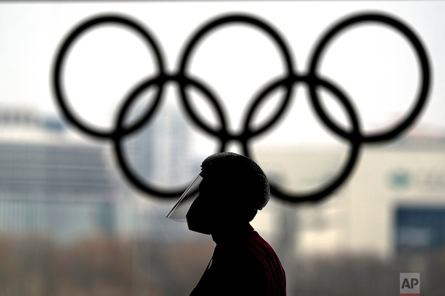  A person wearing a face shield walks past the Olympic rings inside the main media center at the 2022 Winter Olympics, Wednesday, Jan. 19, 2022, in Beijing. (AP Photo/David J. Phillip) 