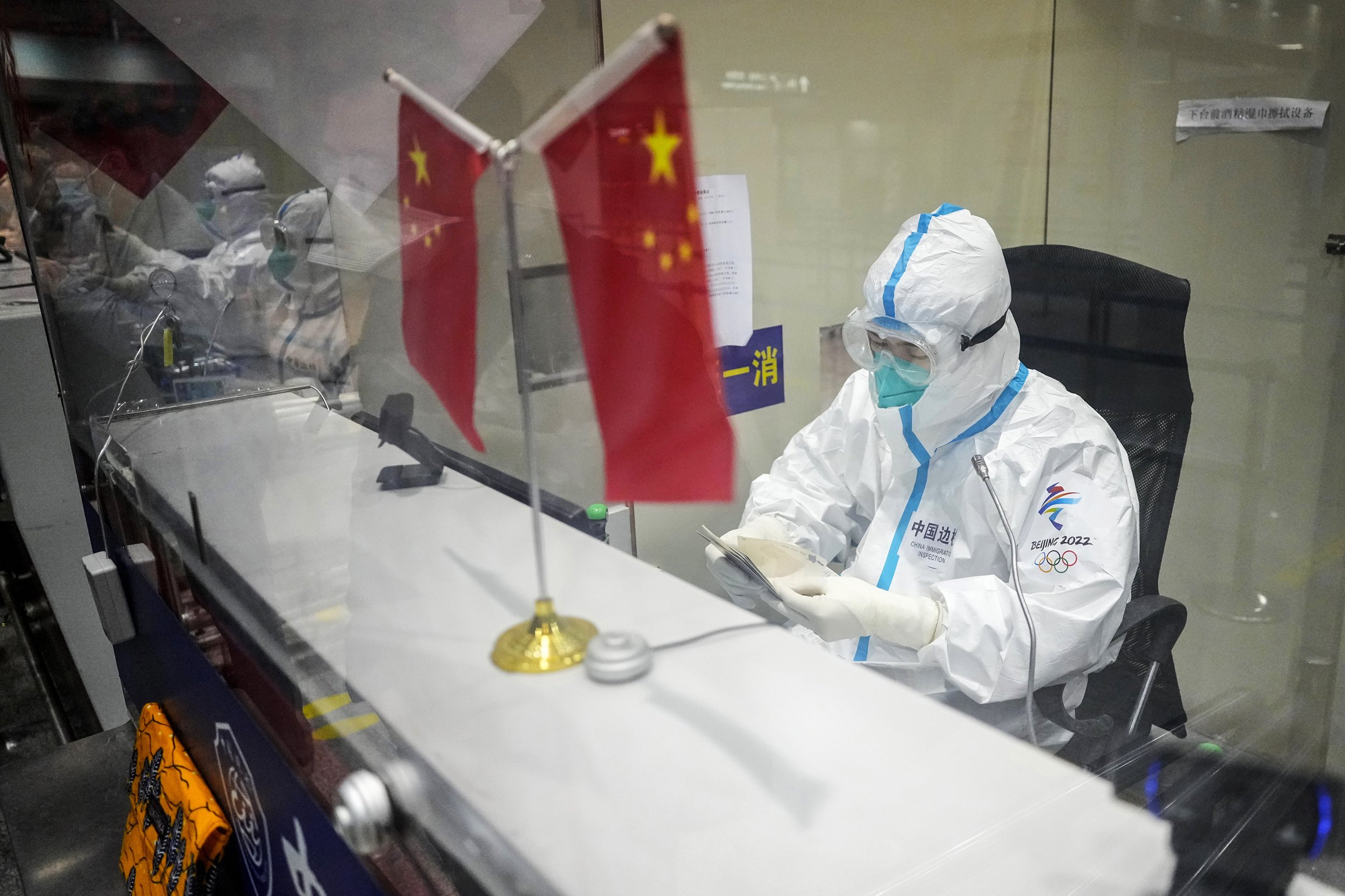  An immigration officer checks documents at the Beijing Capital International Airport ahead of the 2022 Winter Olympics, Tuesday, Feb. 1, 2022, in Beijing. (AP Photo/Pavel Golovkin) 