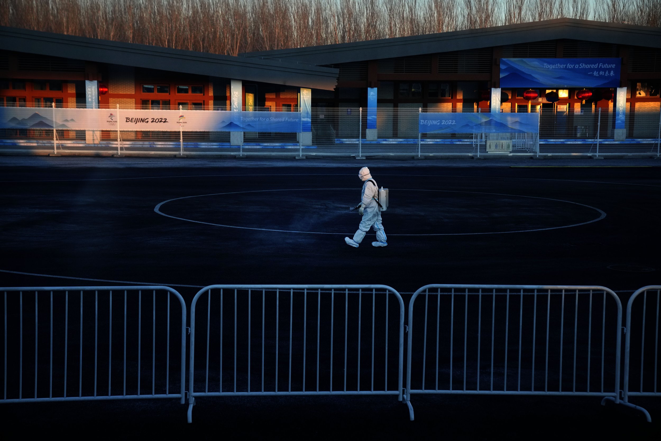  A worker wearing a protective suit sprays disinfectant at a screening checkpoint for arriving athletes at the 2022 Winter Olympics, Tuesday, Feb. 1, 2022, in the Yanqing district of Beijing. (AP Photo/Mark Schiefelbein) 
