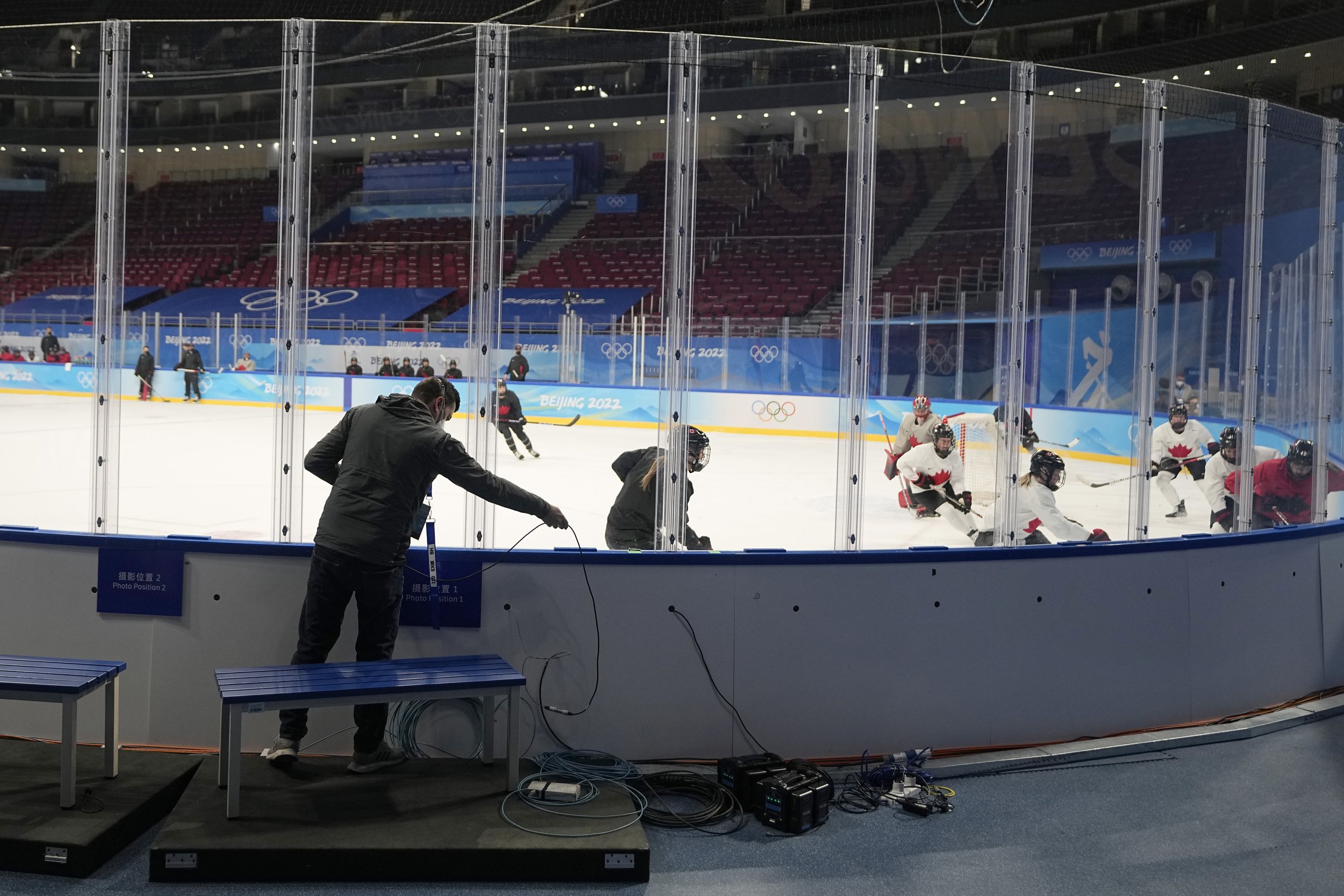  A member of the broadcast crew installs cable as Canada's women's hockey team practice on the ice at the 2022 Winter Olympics, Jan. 30, 2022, in Beijing. (AP Photo/Jeff Roberson) 