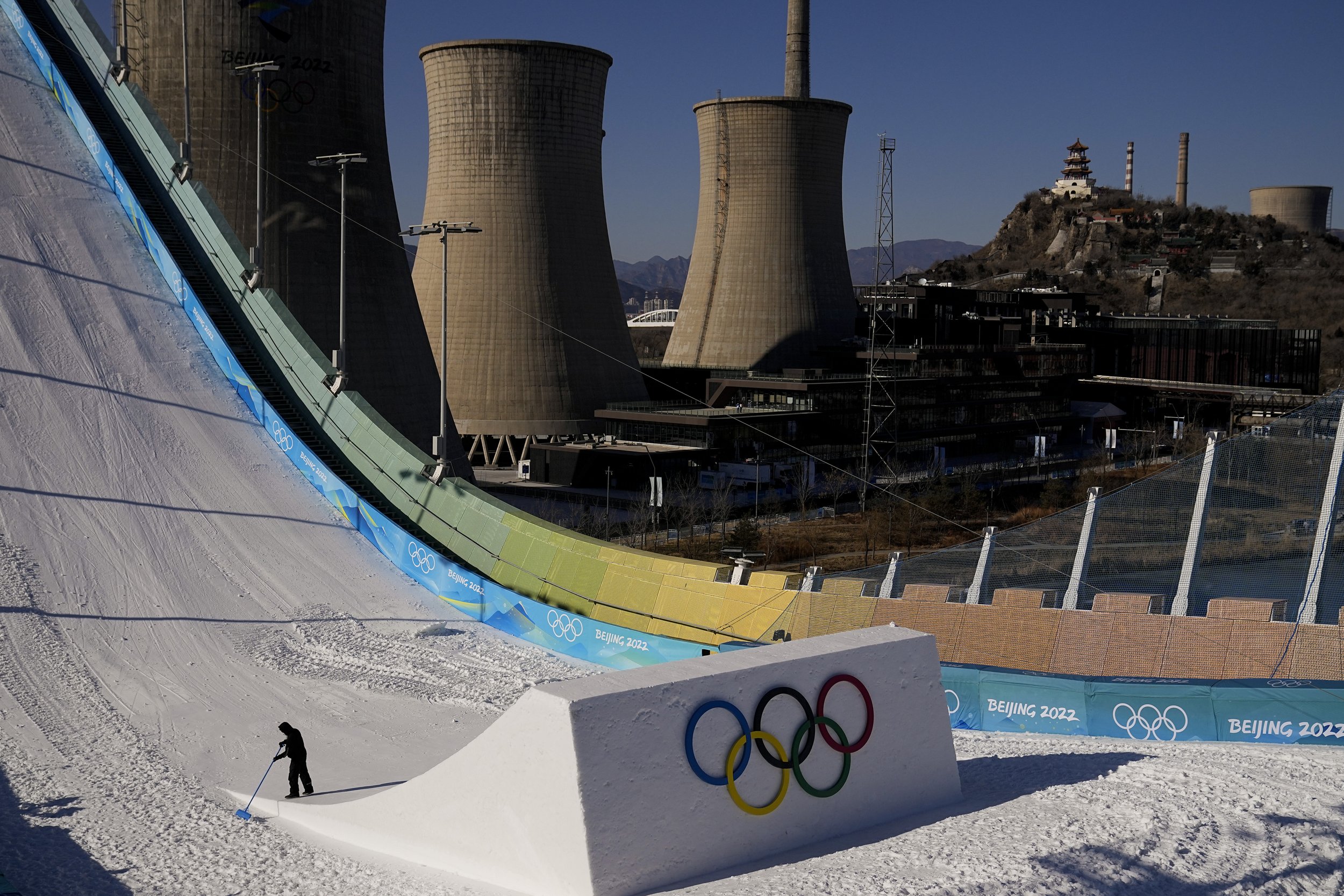  A worker shapes the kicker at the Big Air Shougang ahead of the 2022 Winter Olympics, Feb. 1, 2022, in Beijing, as the old cooling towers of a steel plant stand in the city's former industrial district. (AP Photo/Jae C. Hong) 