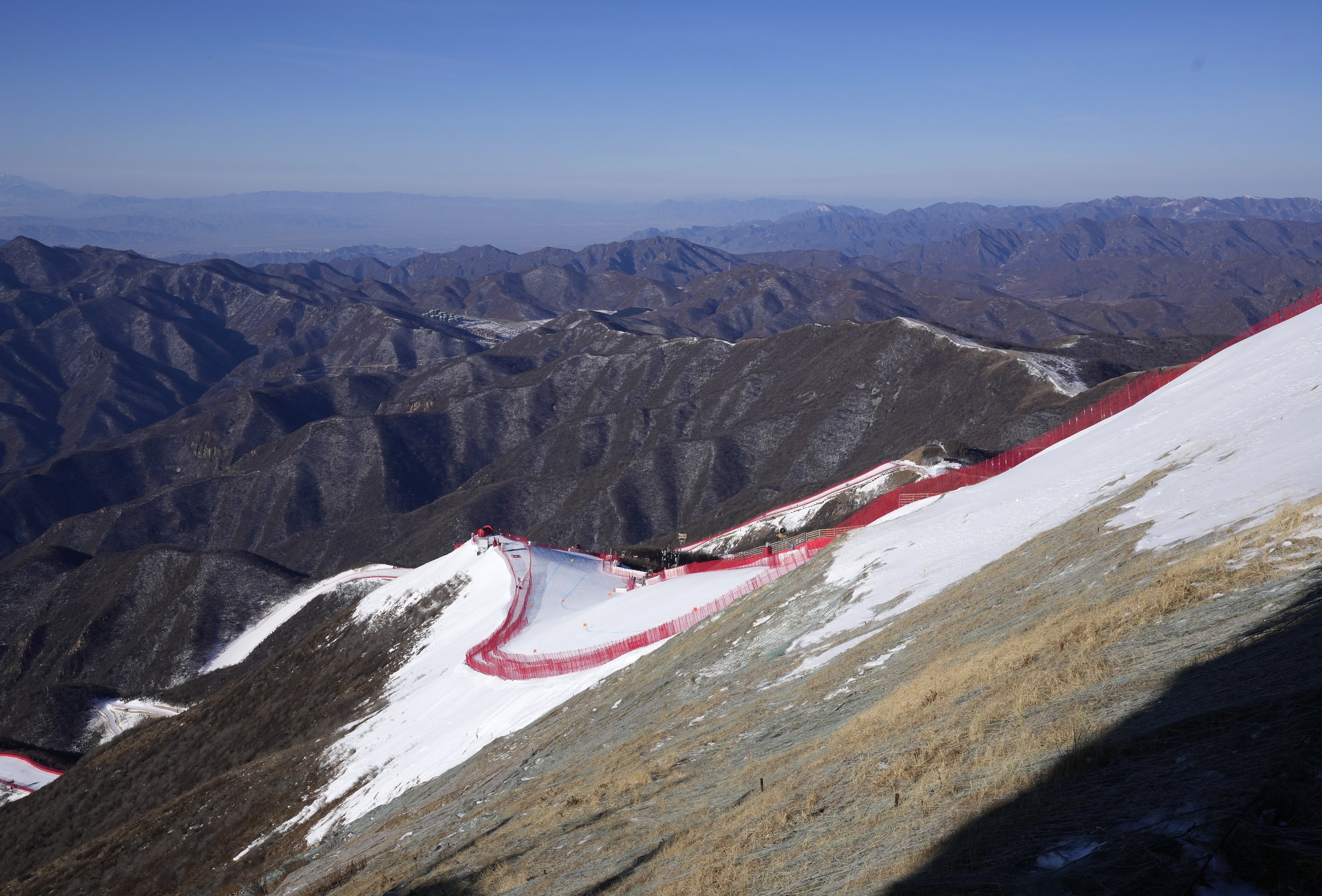  The downhill course stands out from the almost snowless landscape ahead of the first men's downhill training run at the 2022 Winter Olympics, Feb. 3, 2022, in the Yanqing district of Beijing. (AP Photo/Luca Bruno) 